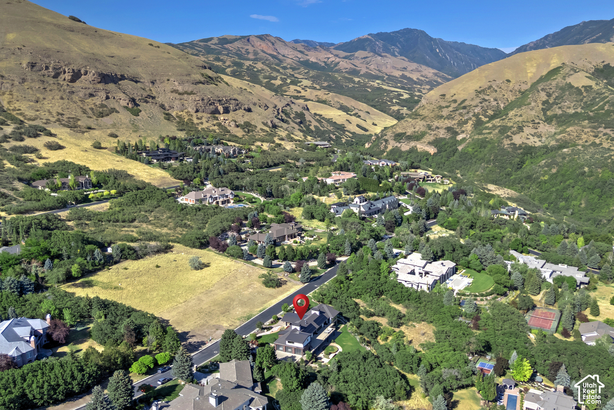 Aerial view of the marked home among hillside residences, with mountains rising behind the neighborhood.