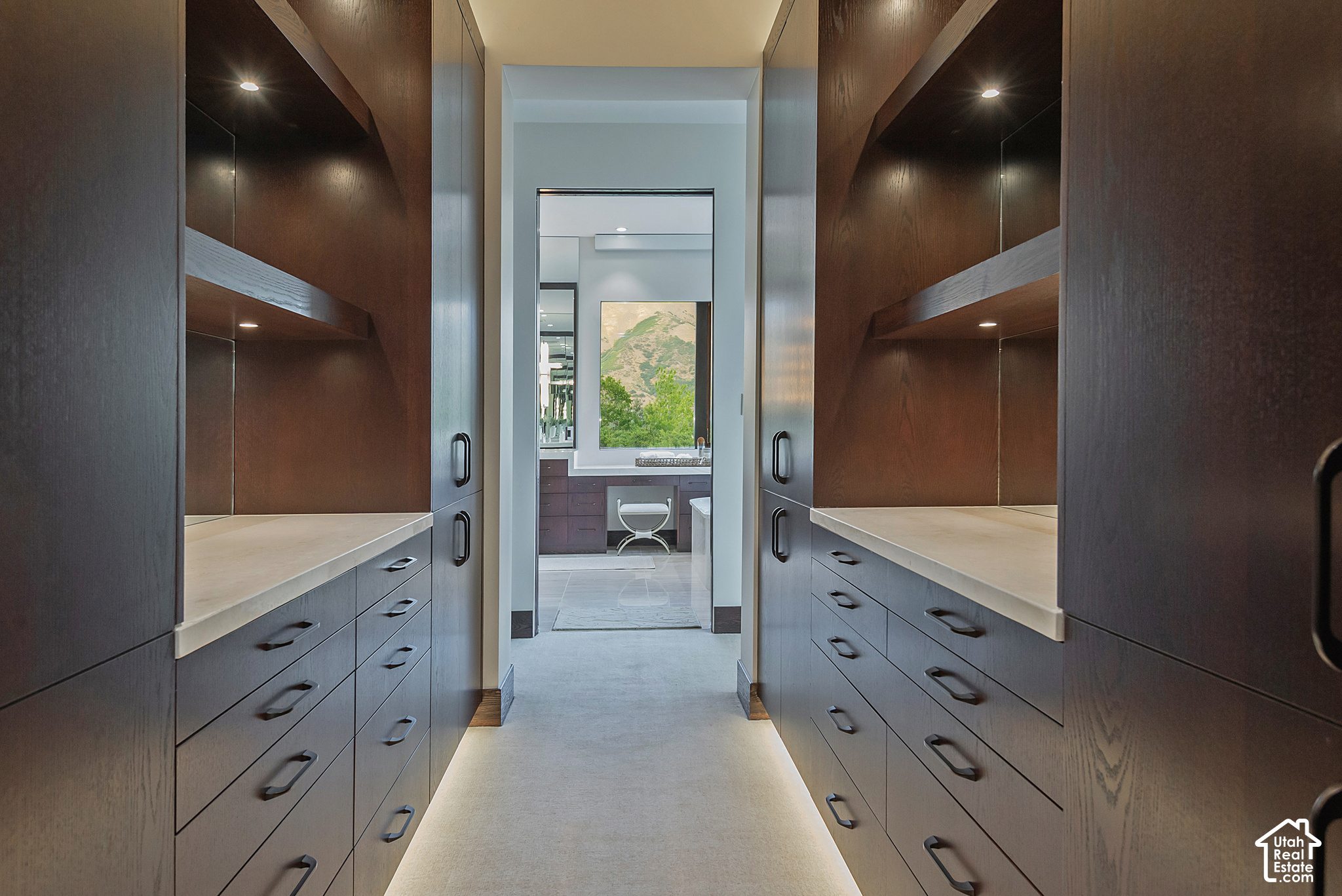 Walk-in dressing room with dark wood built-ins, mirrored panels, and a view through to a mountain-facing bathroom.