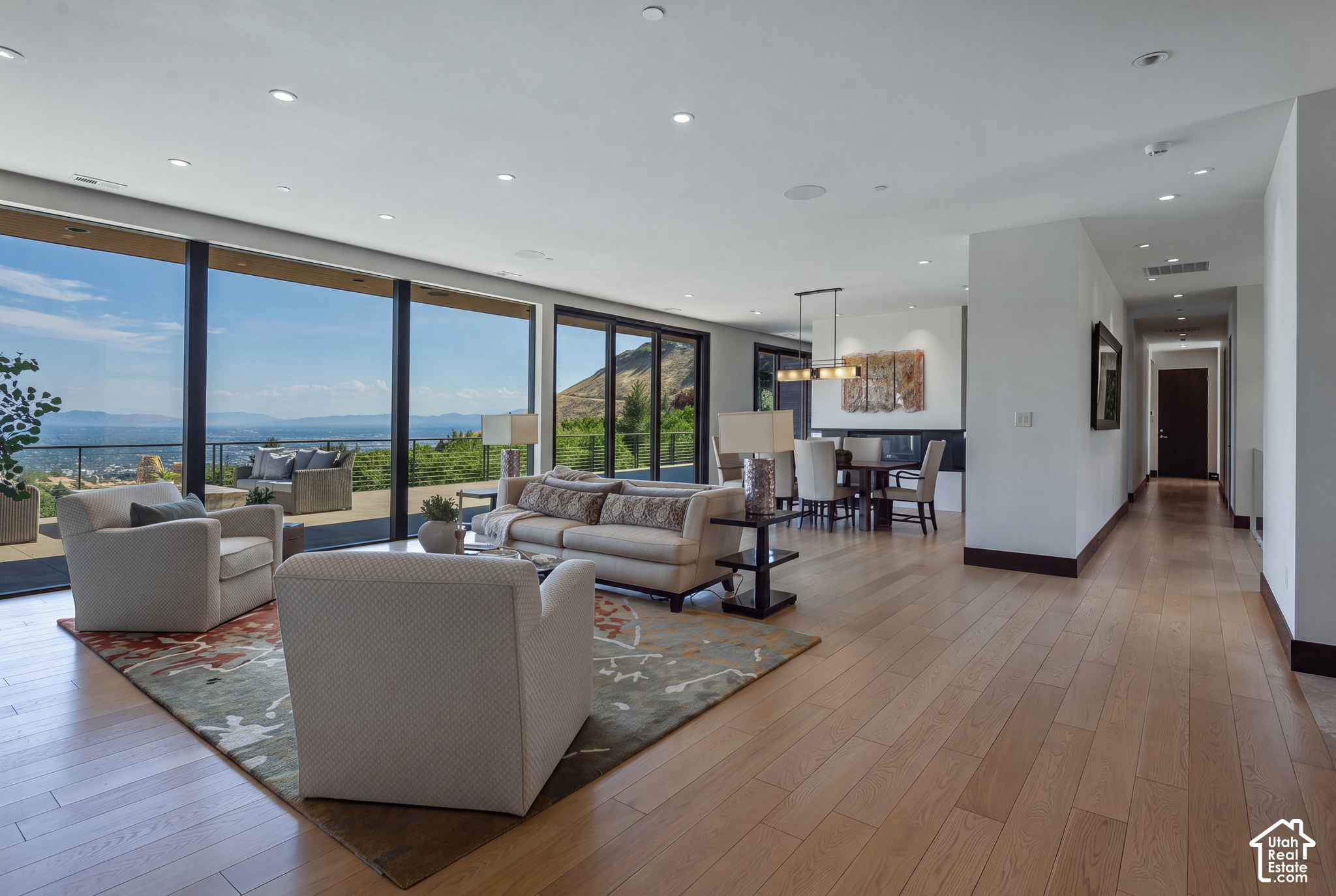 Furnished living room with floor-to-ceiling windows overlooking water, mountains, and the city.