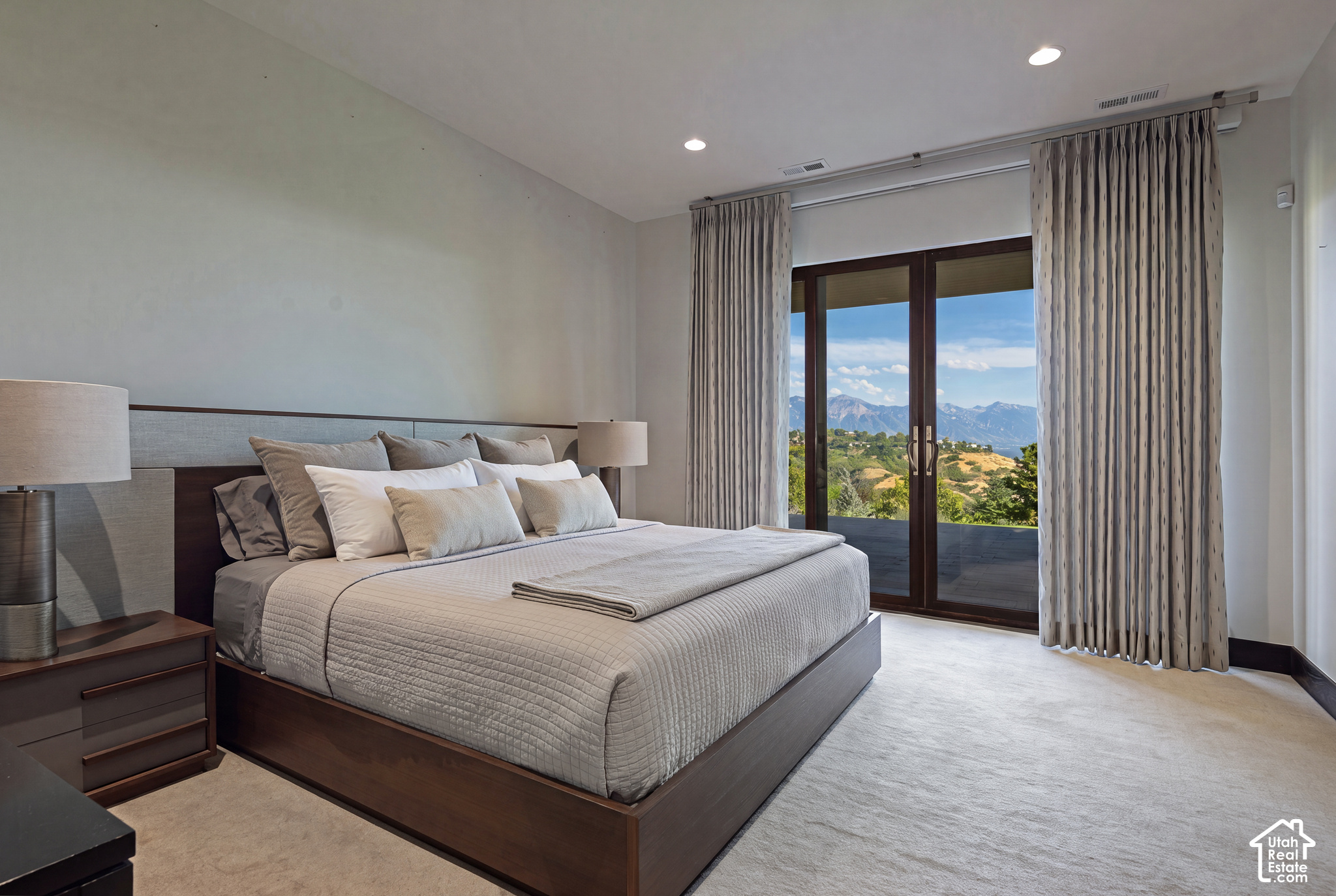 Furnished bedroom with a large bed and glass doors framing a mountain view.