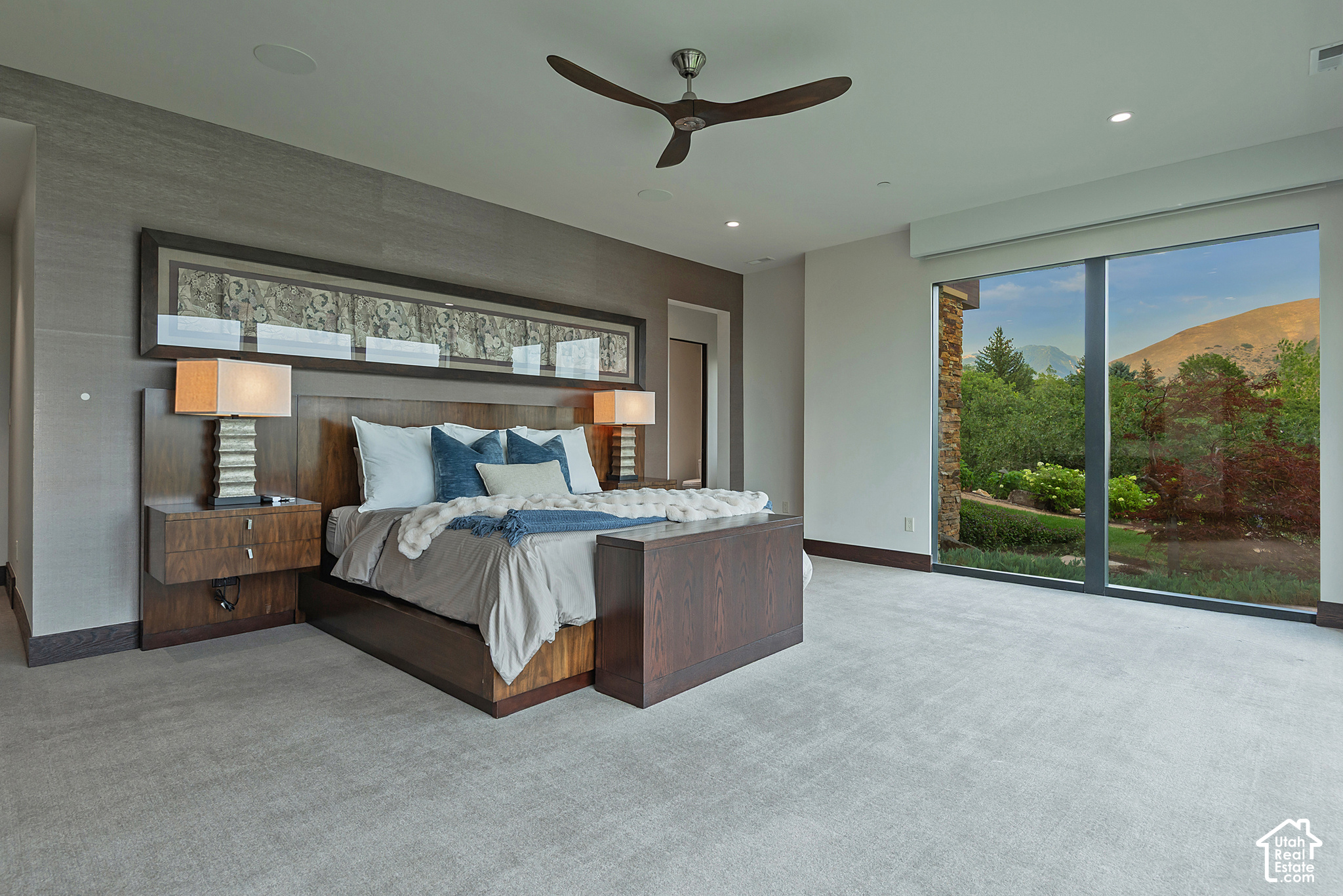 Furnished bedroom with a dark wood bed and sliding glass doors overlooking trees and a mountain.