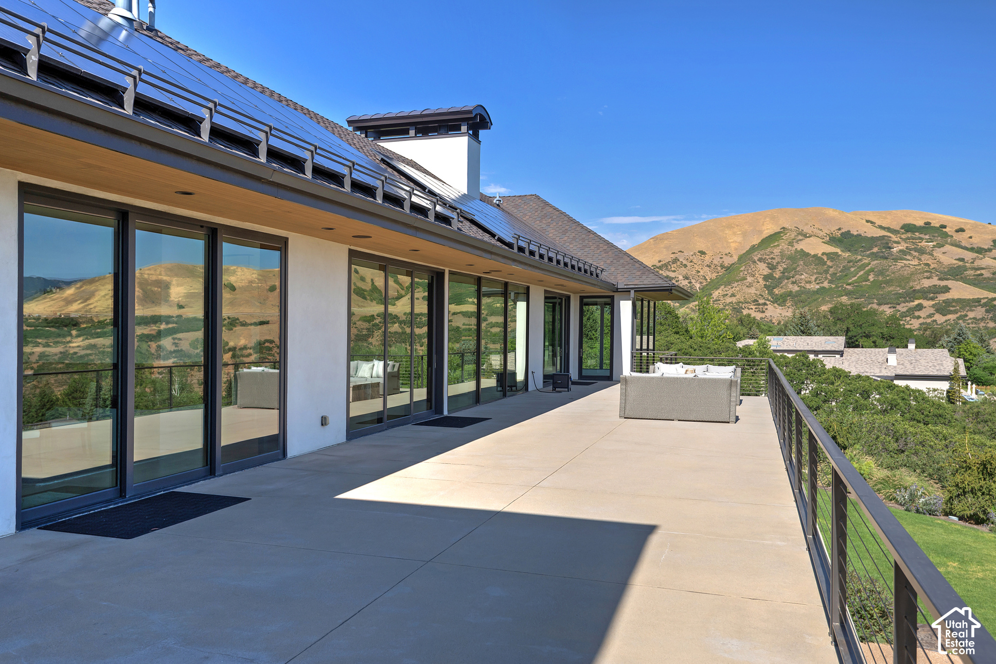 Modern home’s broad terrace with solar panels, outdoor seating, and mountain views.