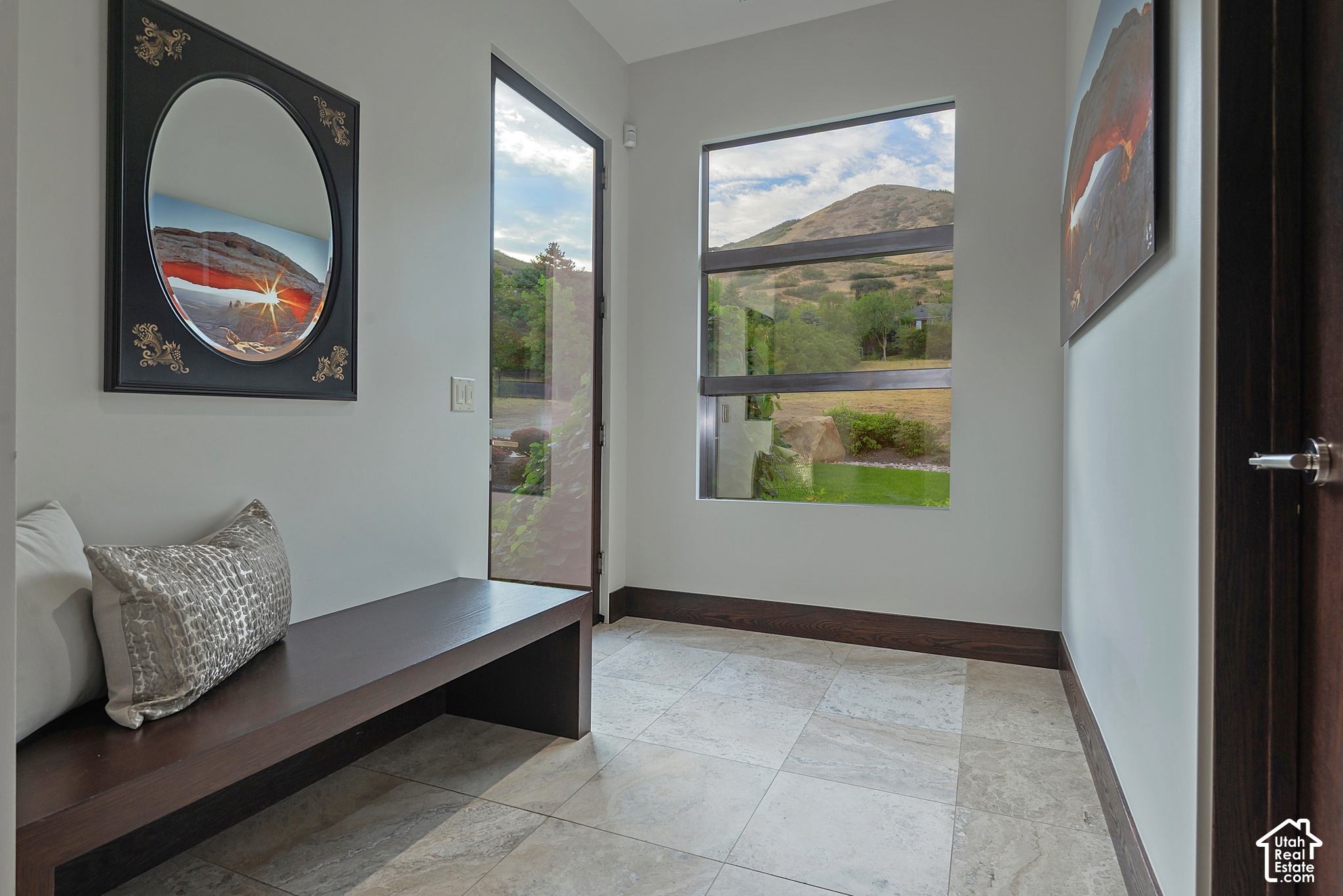 Modern entryway with a built-in wood bench and large windows overlooking a mountain hillside.