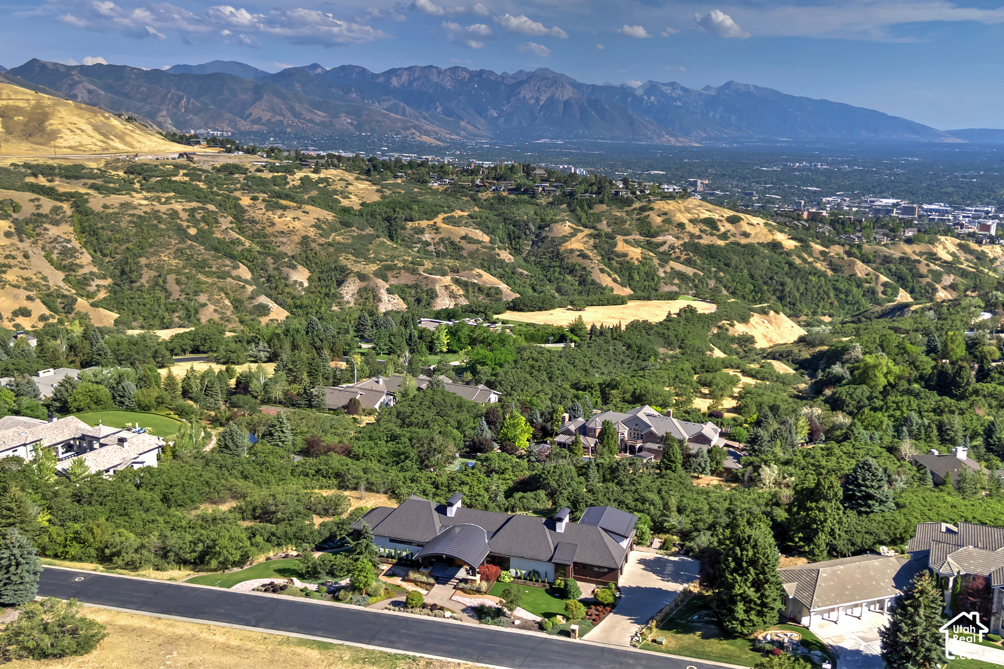 Aerial view of a landscaped home with the Salt Lake Valley and Wasatch Mountains beyond.