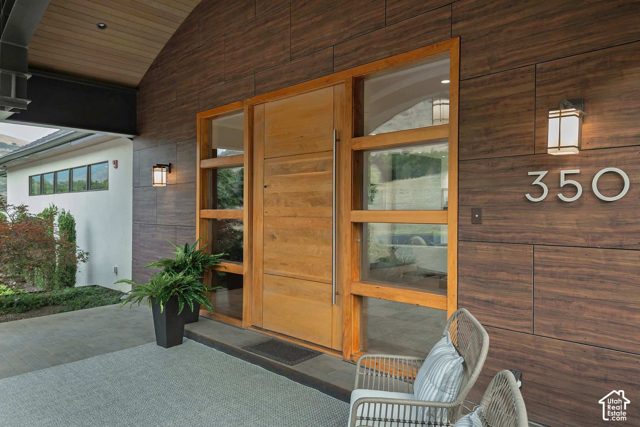 Modern home entrance with a broad wood door, dark siding, and the number 350.