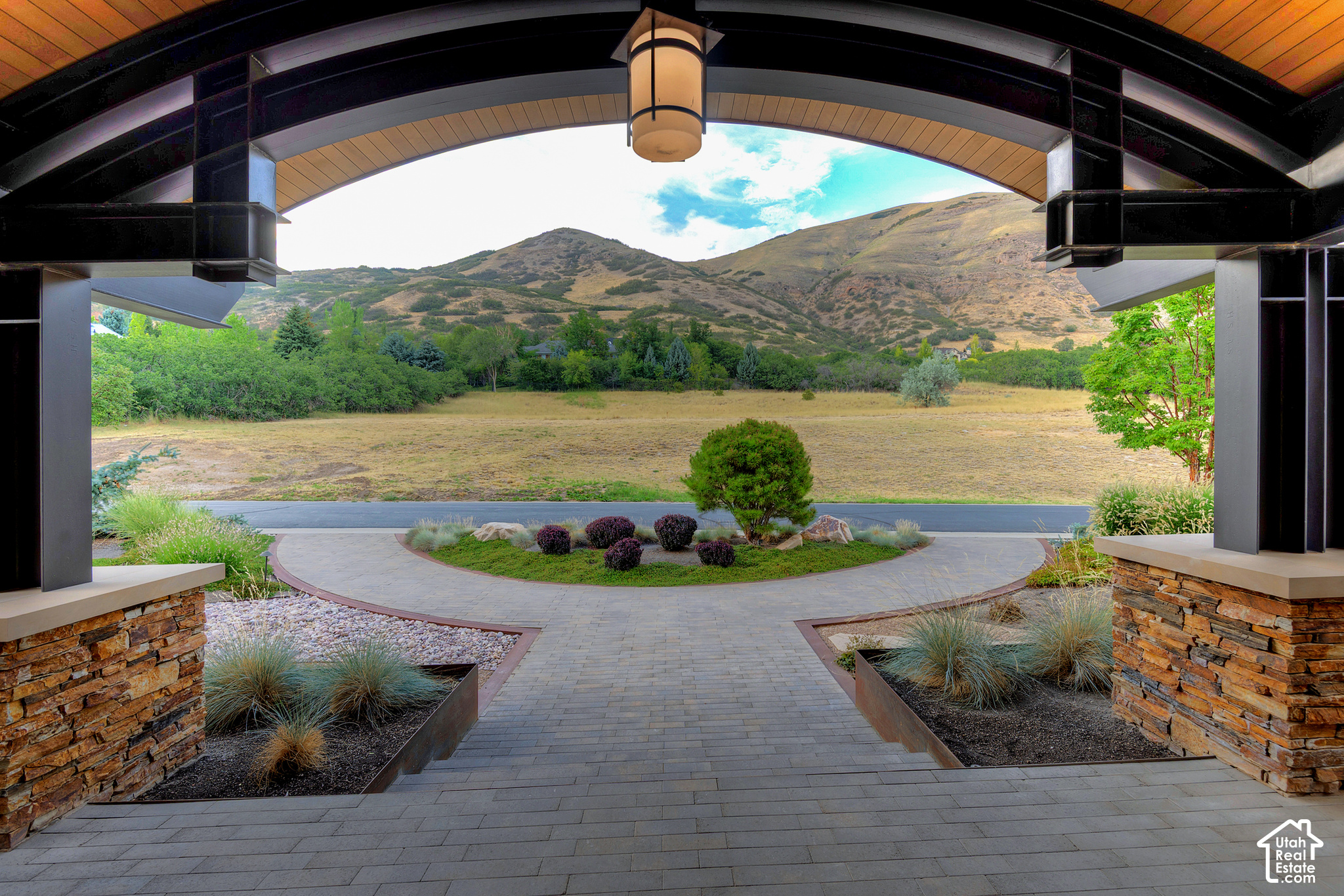 Stone entry patio and curved walkway frame landscaped grounds and mountain views.