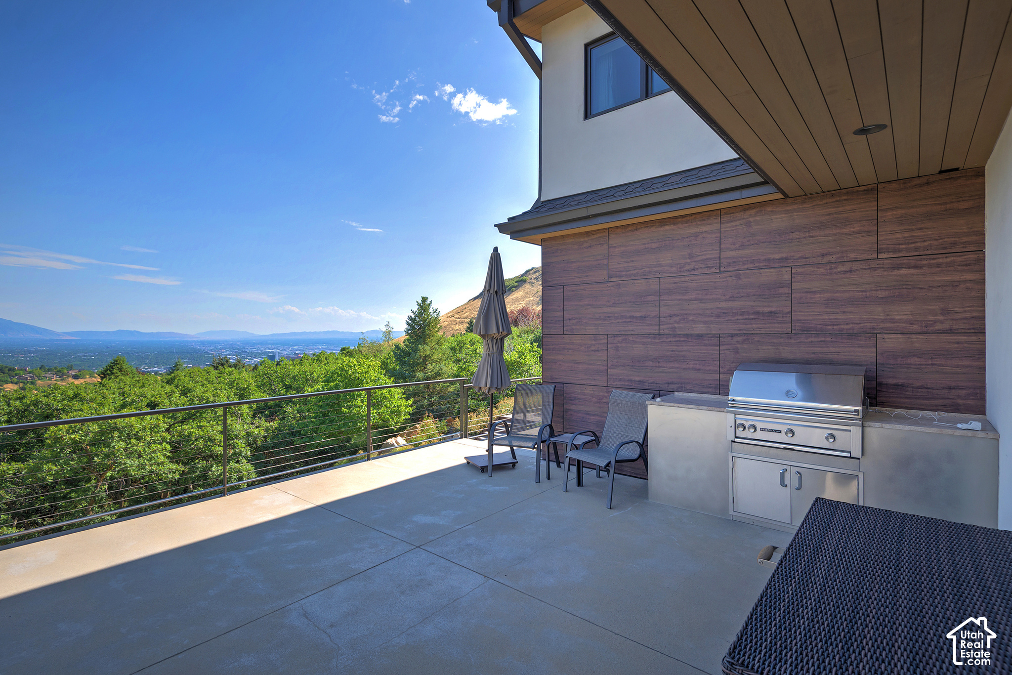 Outdoor terrace with built-in grill and seating overlooking the Salt Lake Valley and distant mountains.