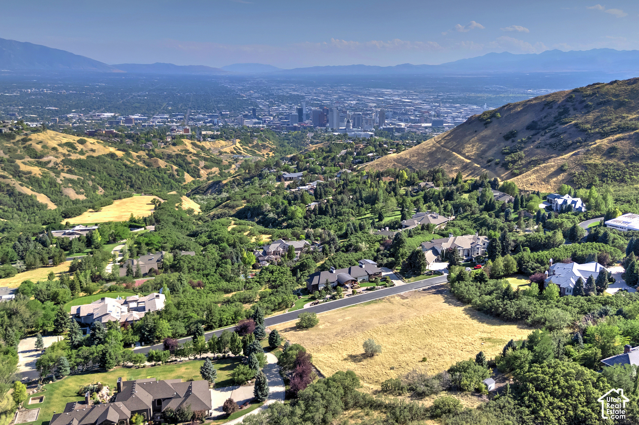 Aerial view of hillside homes and Salt Lake City with mountains beyond.