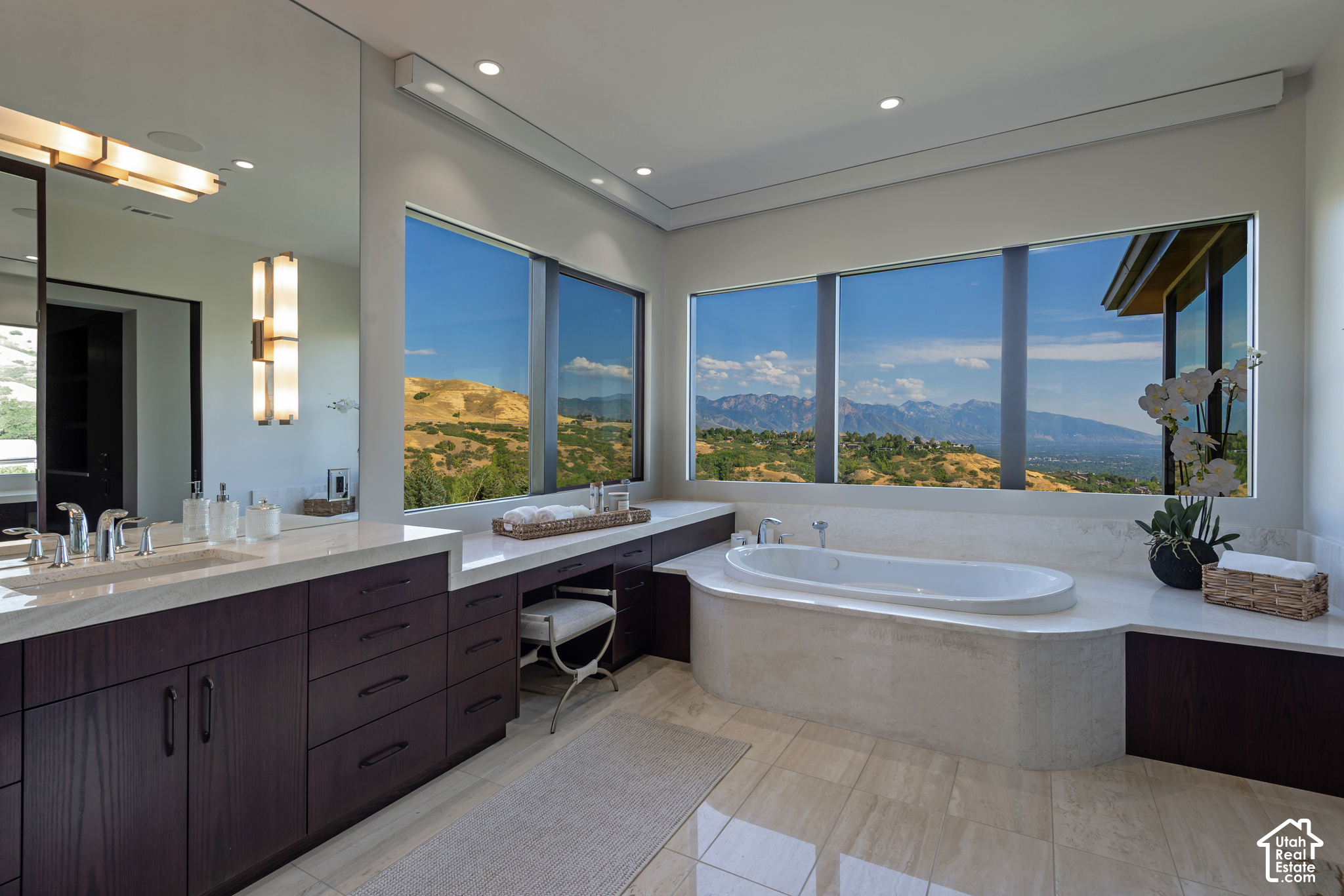 Modern bathroom with a soaking tub and expansive windows overlooking mountain ridges.