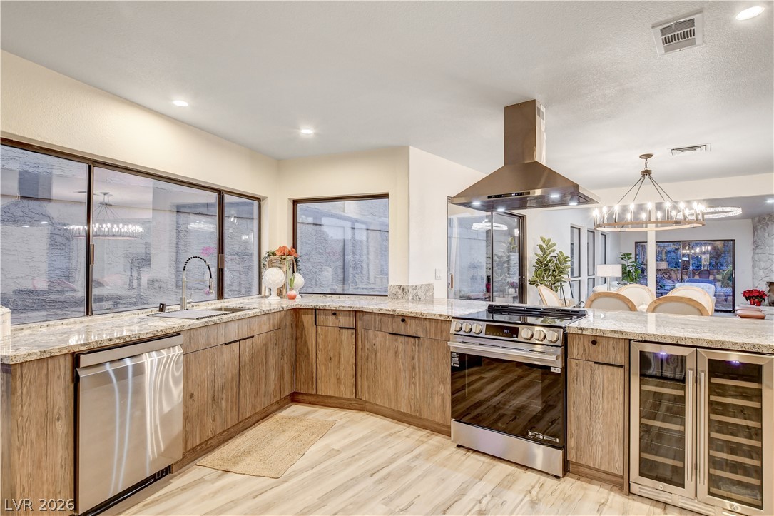 Open kitchen with wood cabinets, stone countertops, stainless appliances, and a built-in wine refrigerator.