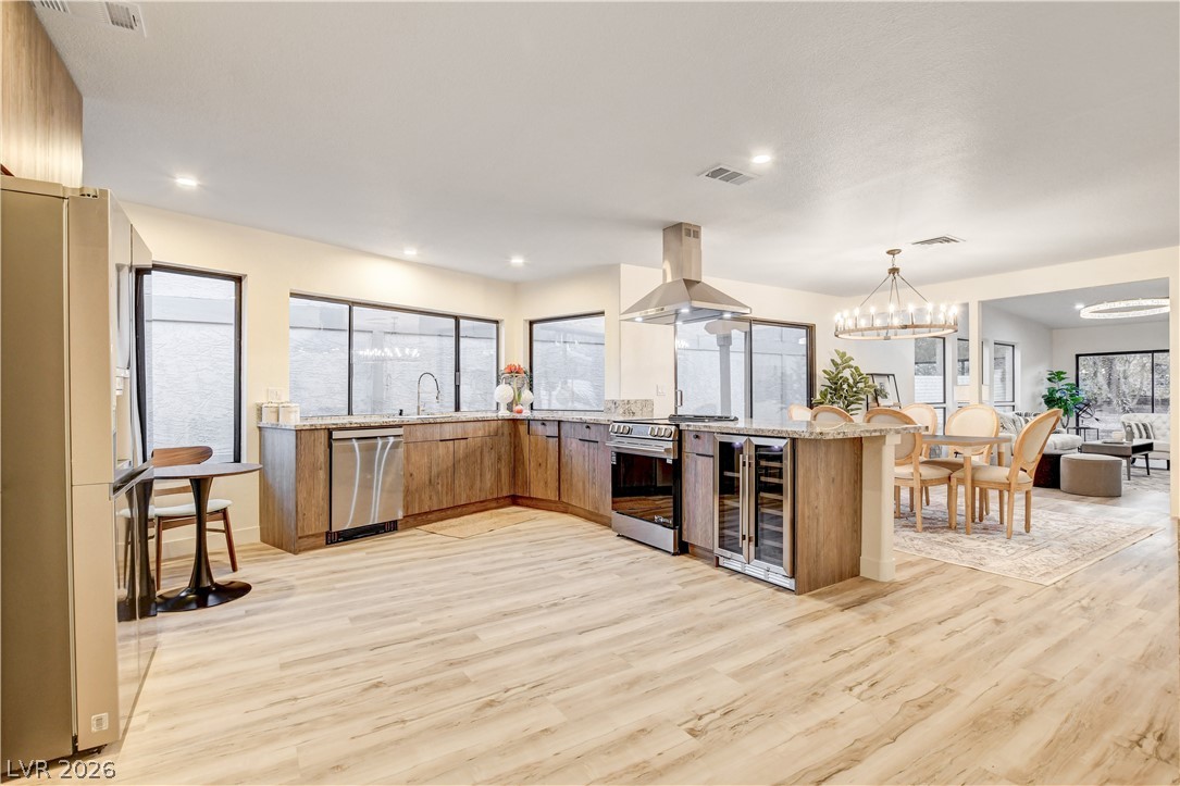 Open-plan kitchen with a large island, wood cabinetry, stainless steel appliances, and adjoining dining area.