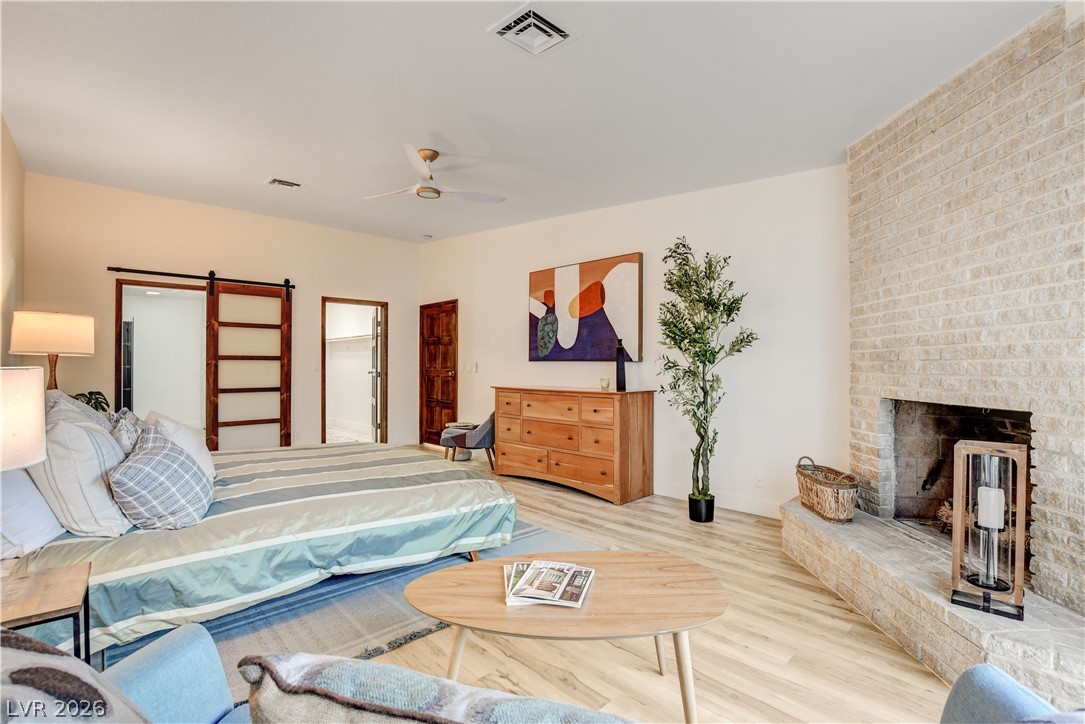 Bedroom with a large bed beside a floor-to-ceiling stone fireplace and sliding barn door.