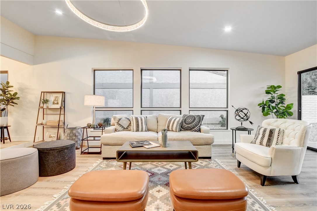 Staged living room with a cream sofa, tufted armchair, patterned rug, and leather ottomans.