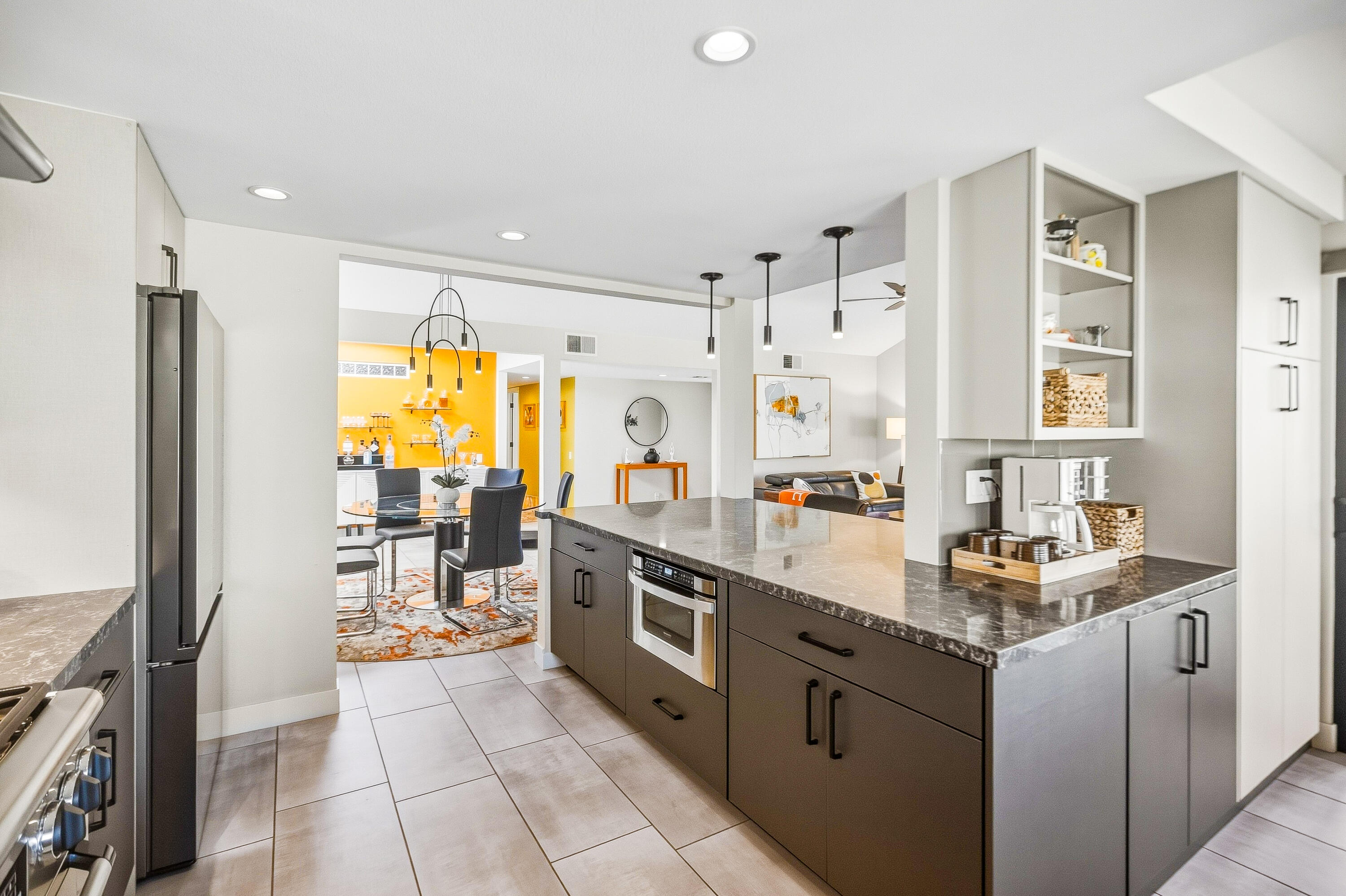 Modern kitchen with a large dark-stone island and open dining area beyond.