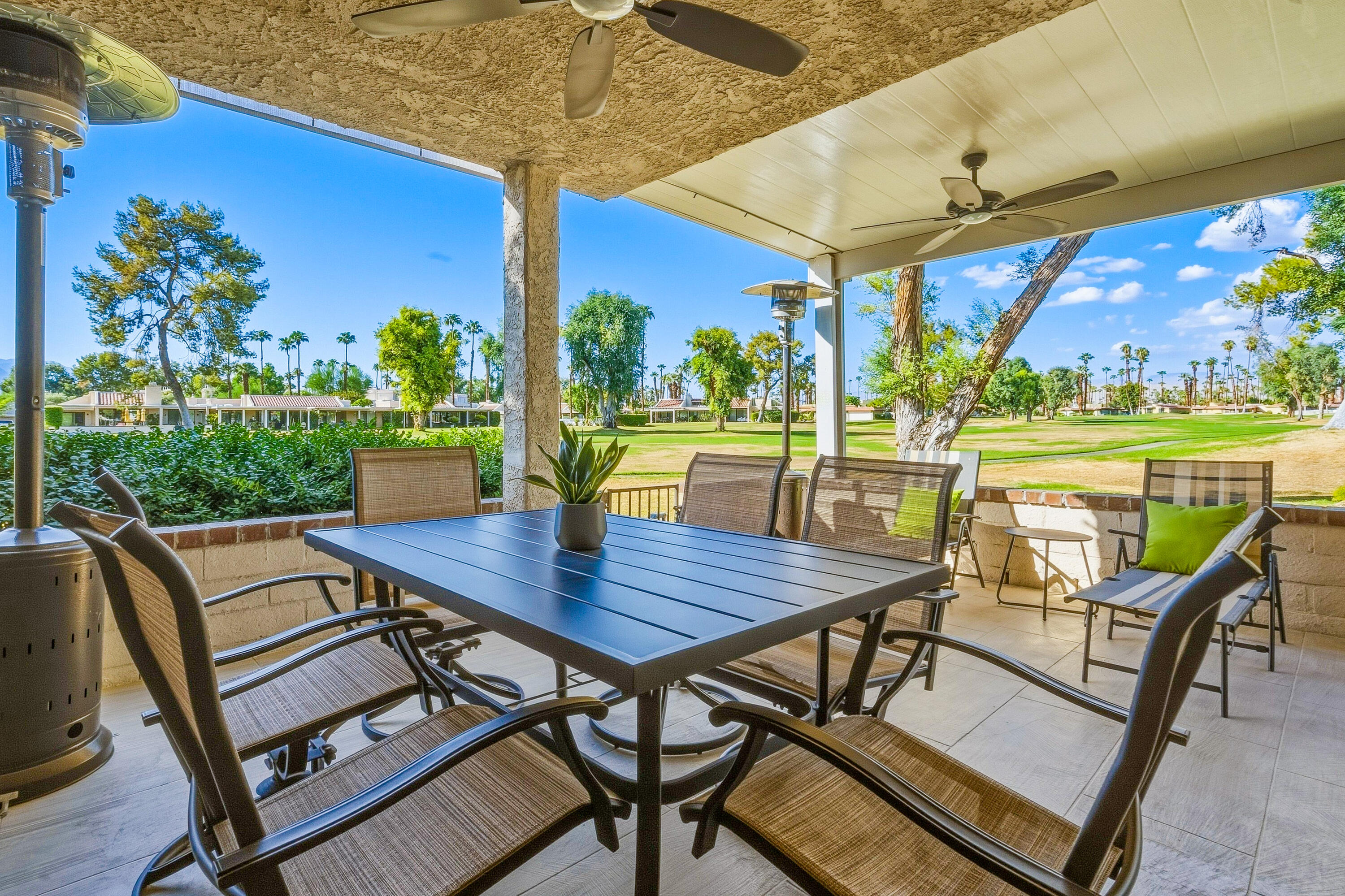 Covered patio dining area with ceiling fans and a golf course view.