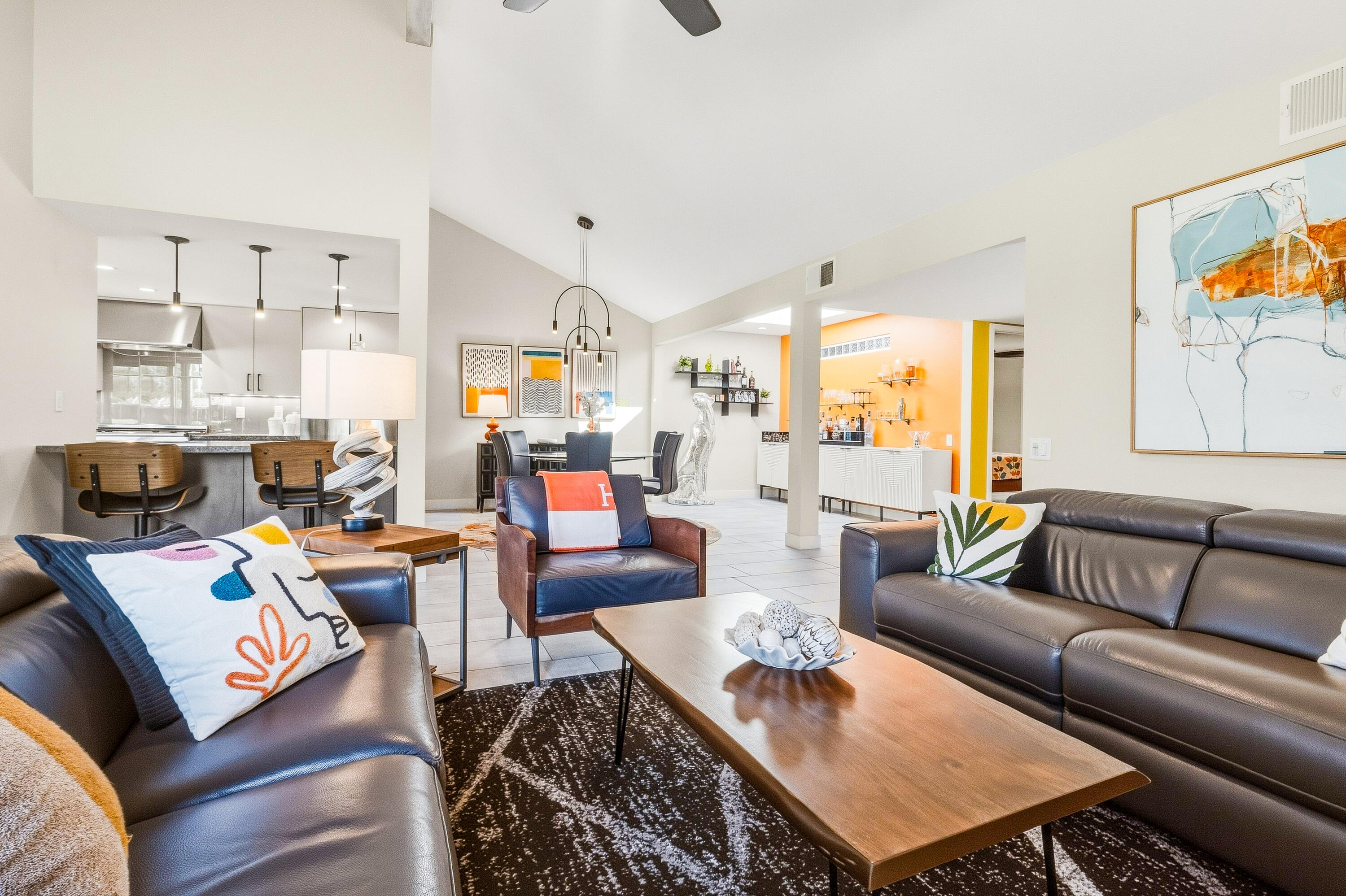 Open-plan living room with leather sofas, a wood coffee table, and a view of the dining area and kitchen.