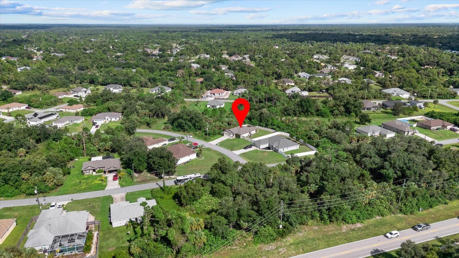Aerial view of the marked home on a wooded lot among North Port residences.