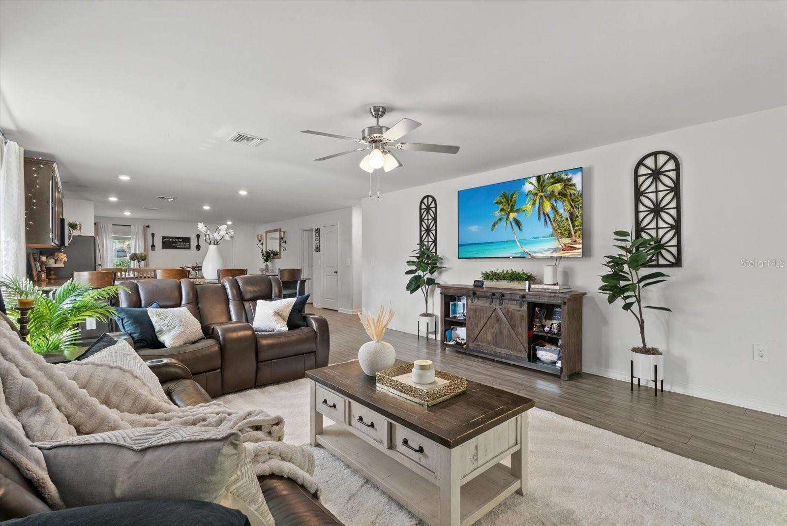 Furnished living room with brown leather recliners, a large coffee table, and tropical wall art.