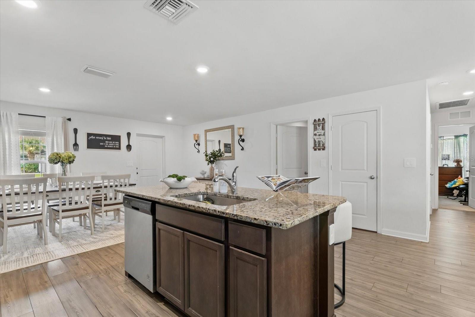 Kitchen with a dark wood island and granite counter opening to a white dining area.