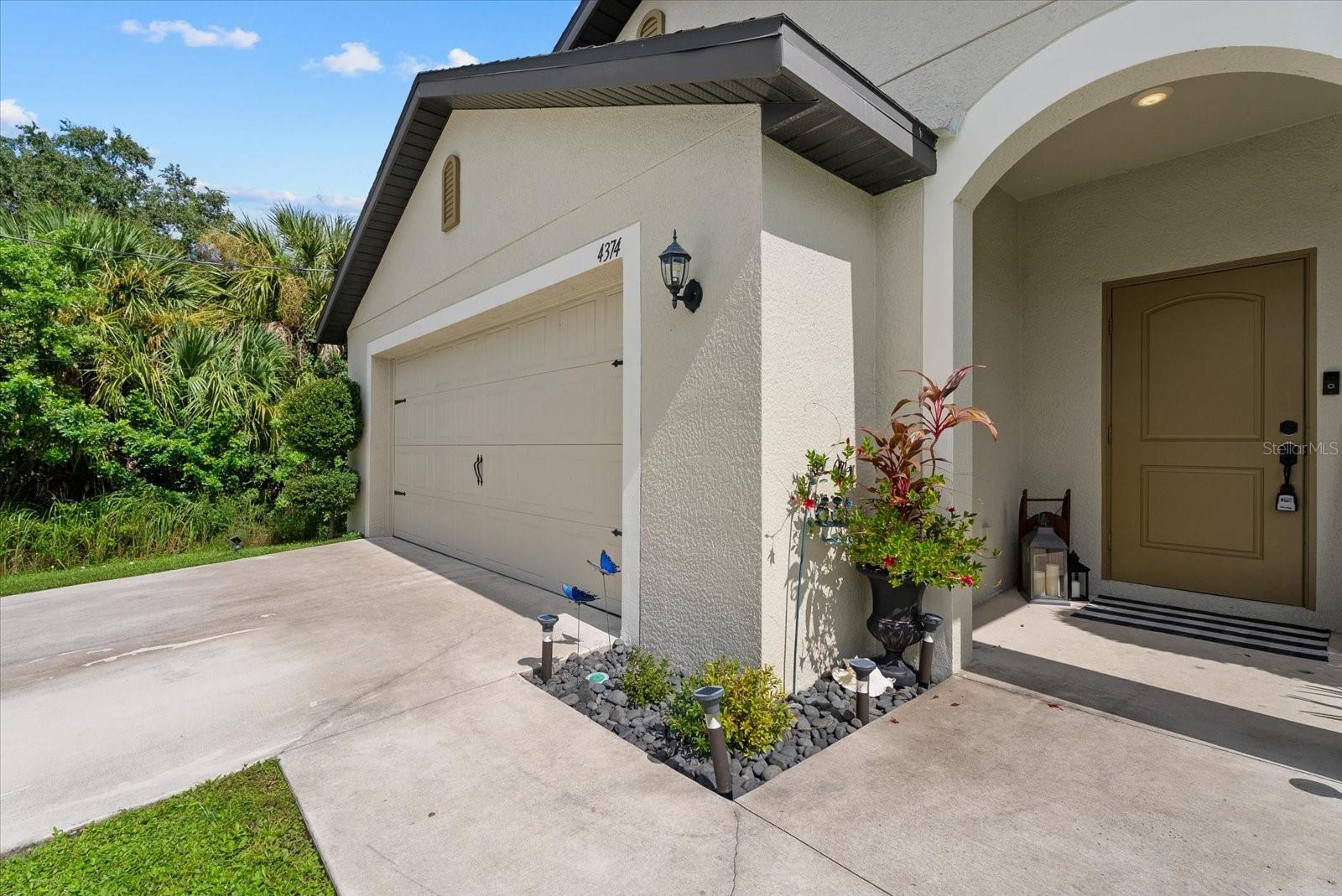 Home exterior with attached garage, covered entry, and landscaped planting beds.