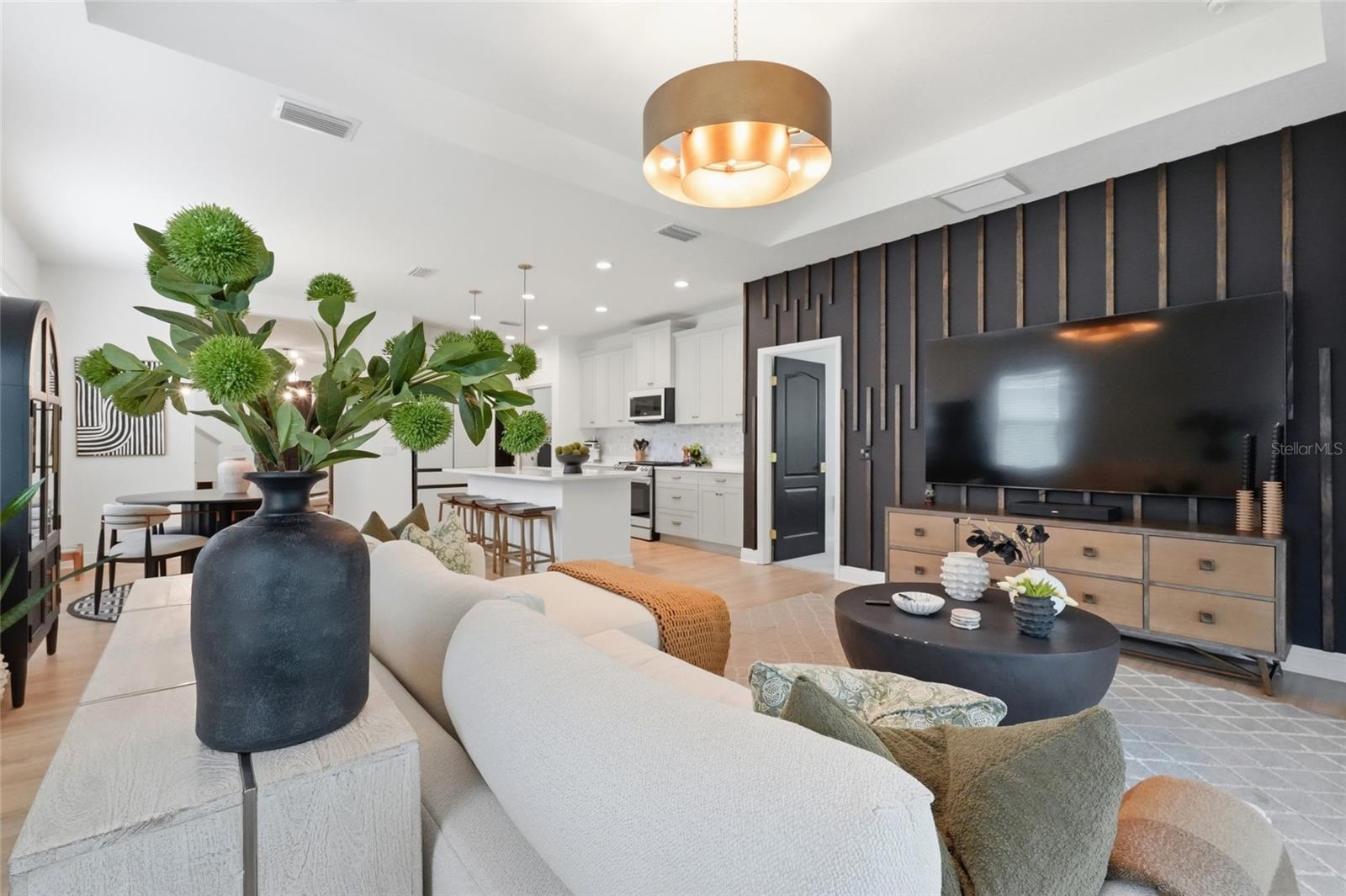 Open-plan living room with a white sectional facing a television wall beside the kitchen island.