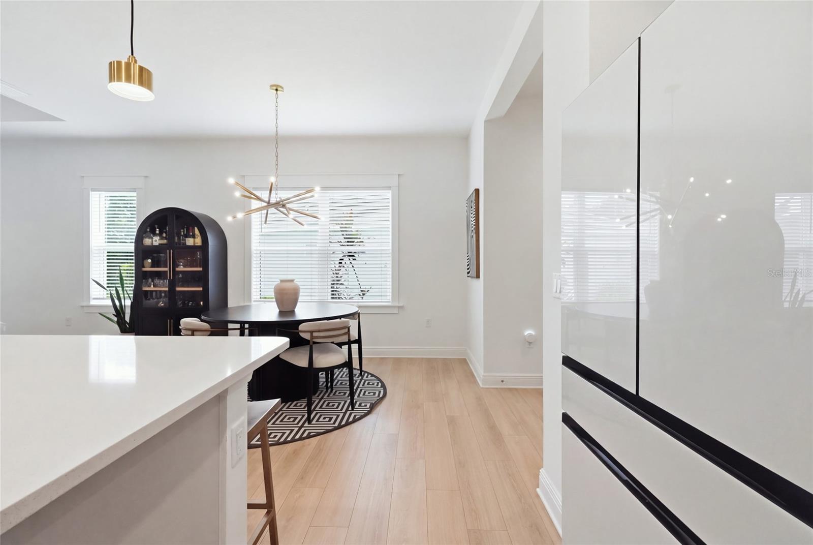 Open kitchen and dining area with a white island, round table, and light wood floors.