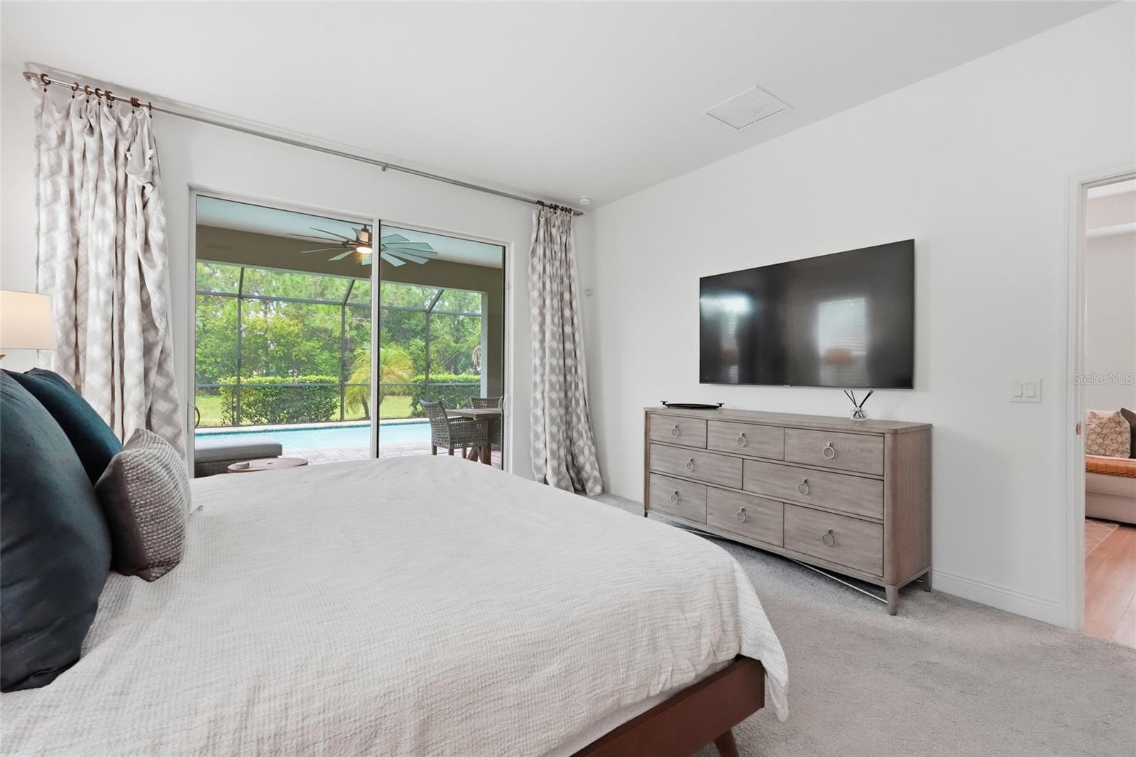 Bedroom with a large bed and sliding doors overlooking a screened pool patio.