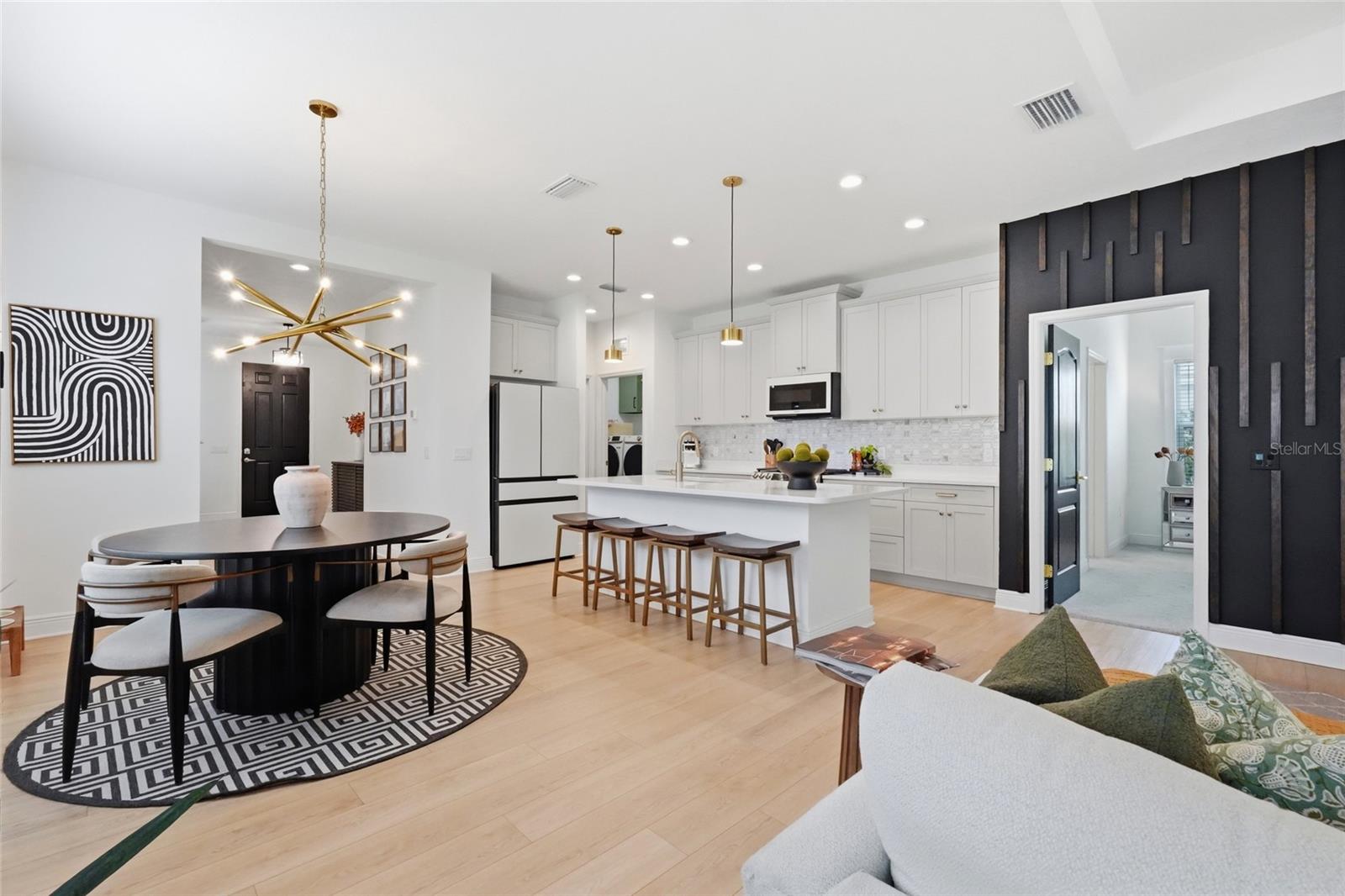 Open-plan kitchen and dining area with a white island, bar stools, and a round dining table.