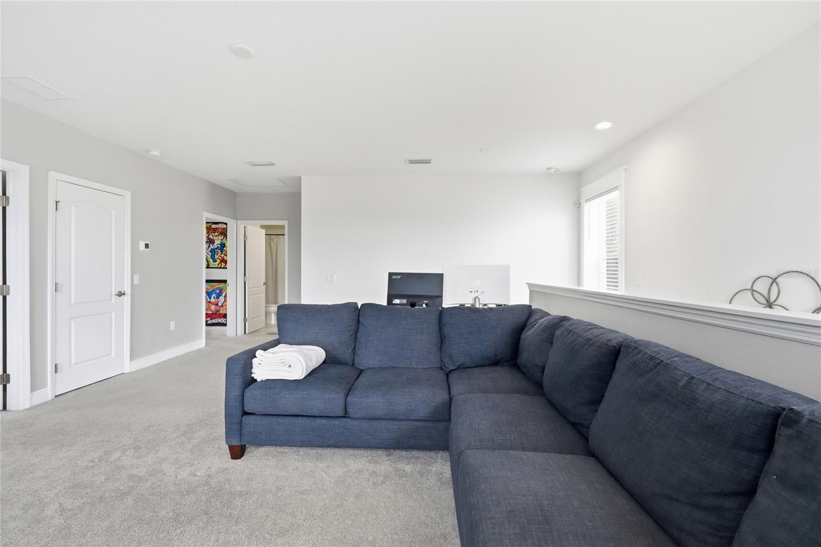 Carpeted living room with a large dark sectional sofa and open doorway.