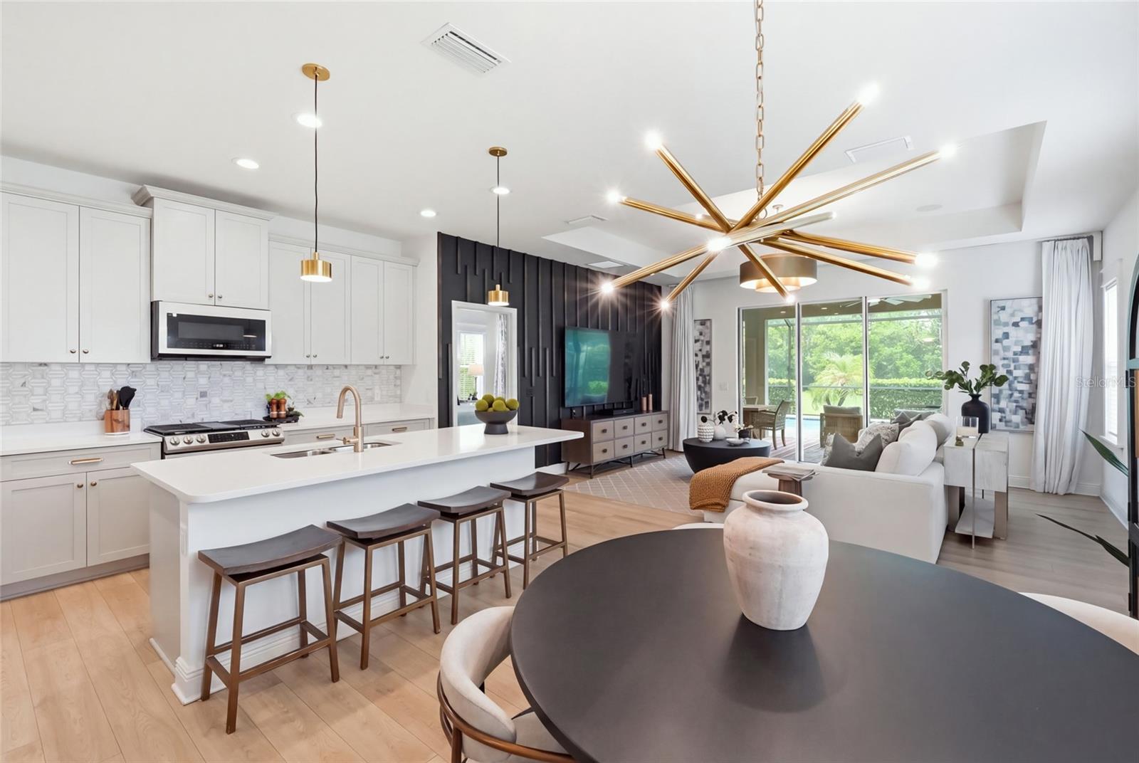 Open-plan kitchen and living room with a large island, dark accent wall, and sliding doors to the patio.
