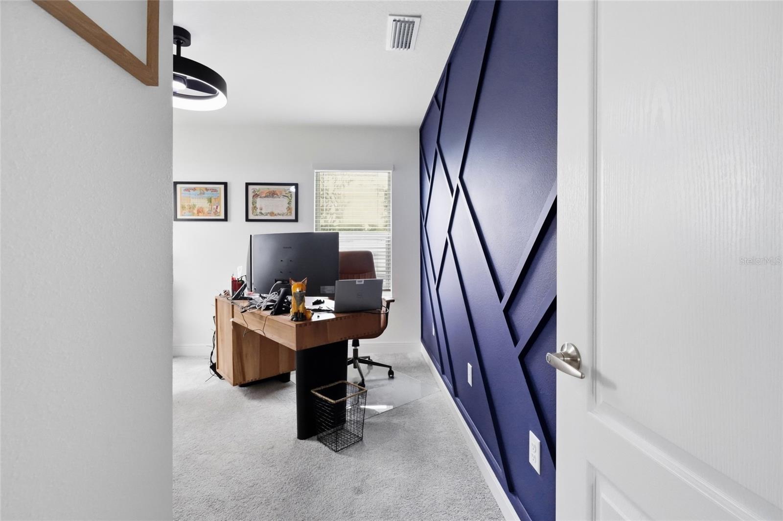 Home office with a navy geometric accent wall and a wooden desk.