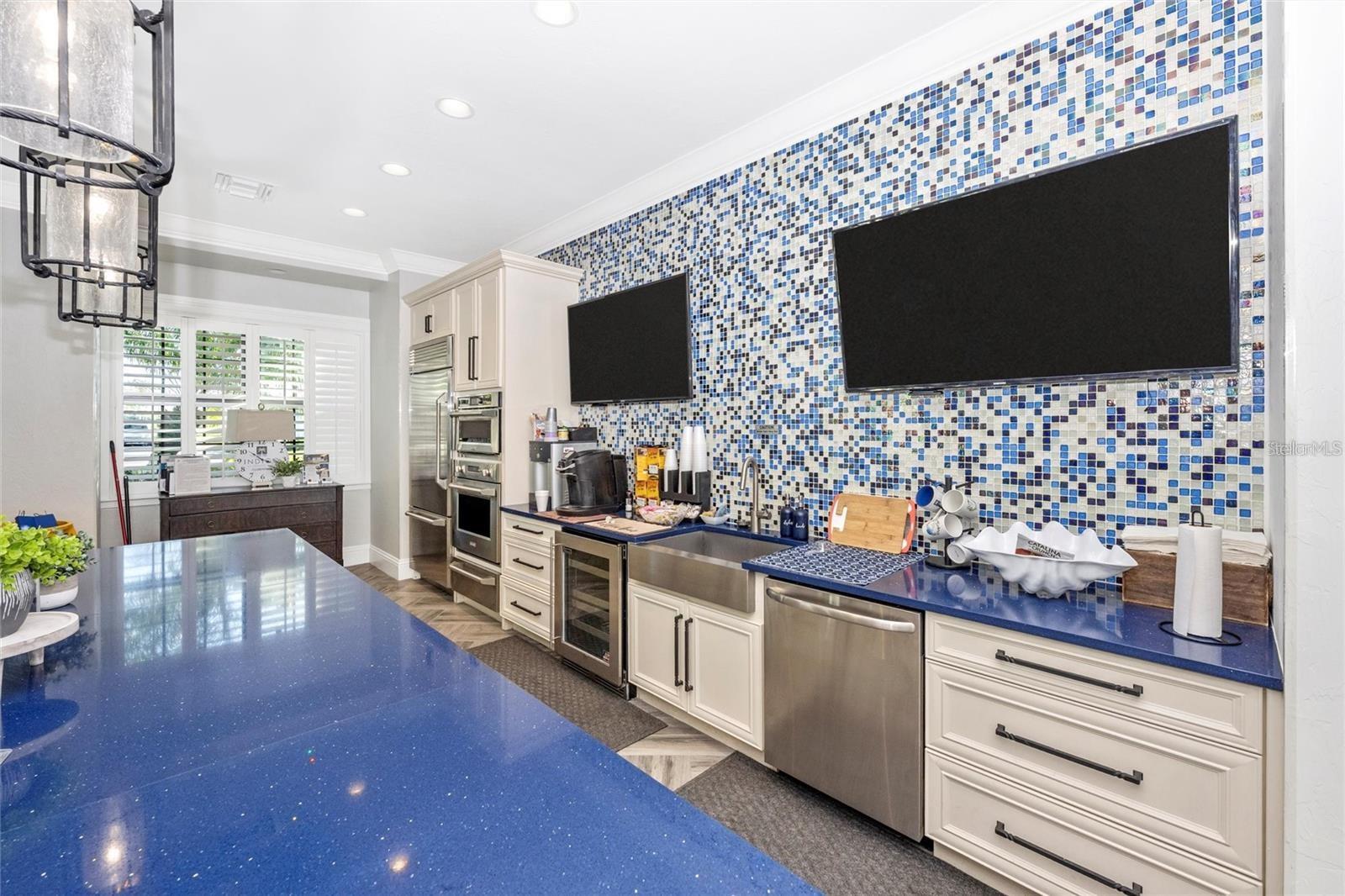 Kitchen with vivid blue counters, white cabinetry, stainless steel appliances, and a mosaic-tile backsplash.