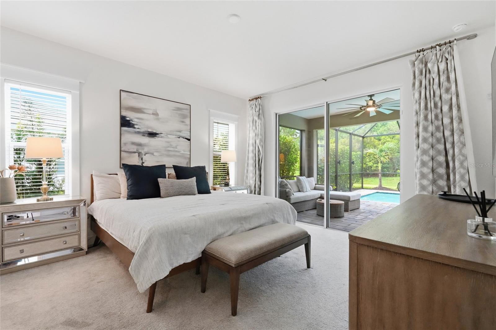 Furnished bedroom with sliding doors opening to a screened lanai and pool.