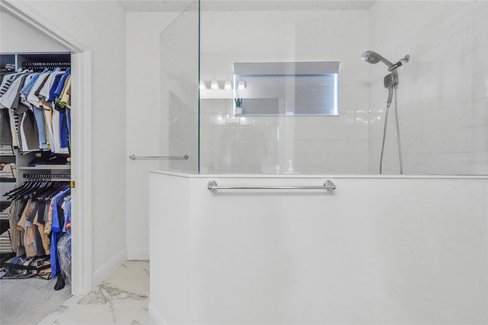 Bathroom with a glass-enclosed shower and a walk-in closet visible through the doorway.