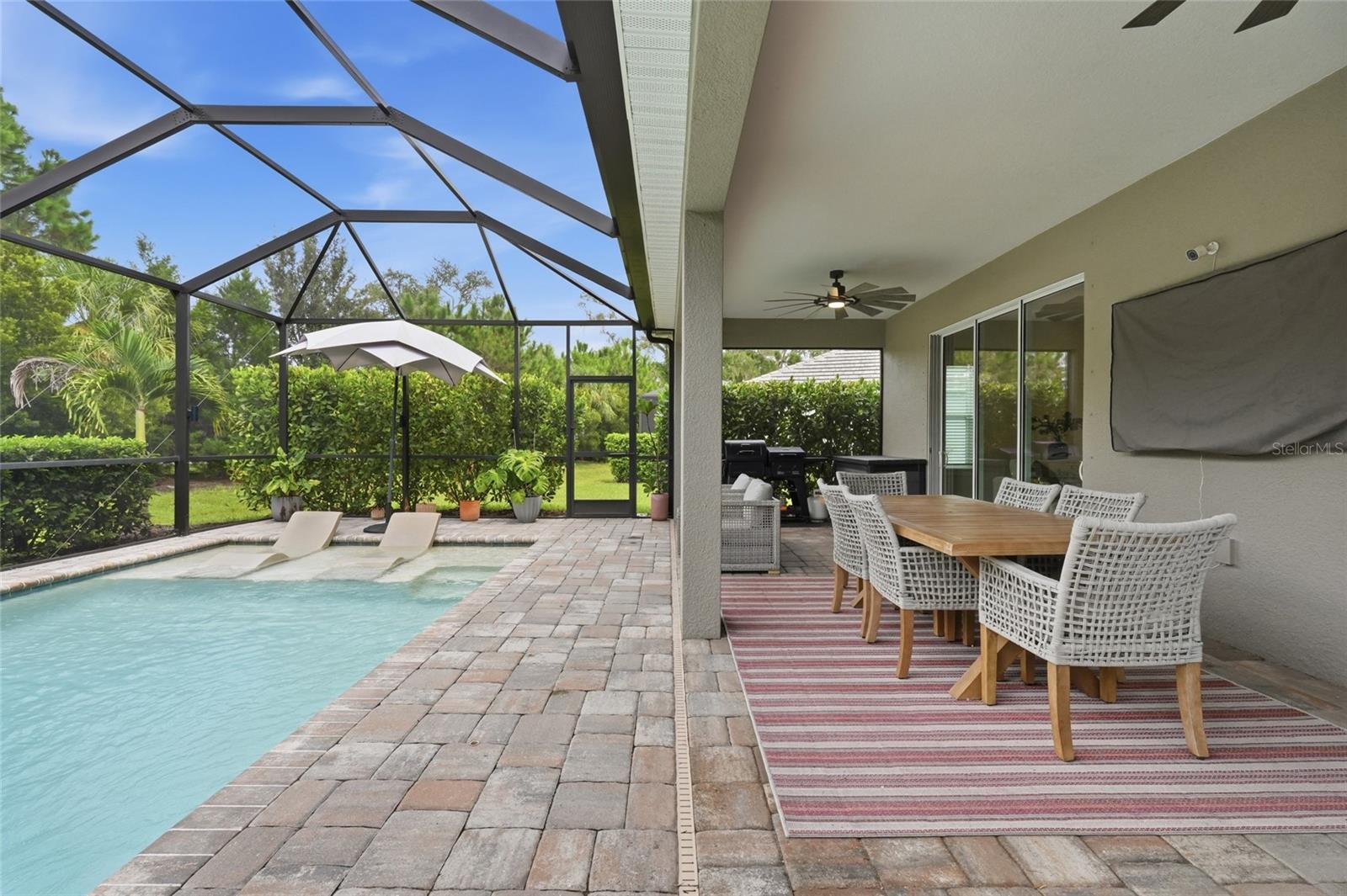 Screened pool and covered patio with in-water loungers and an outdoor dining set.