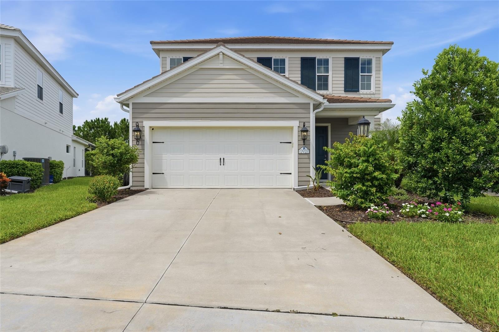 Two-story home with a double garage, wide driveway, and leafy landscaping.