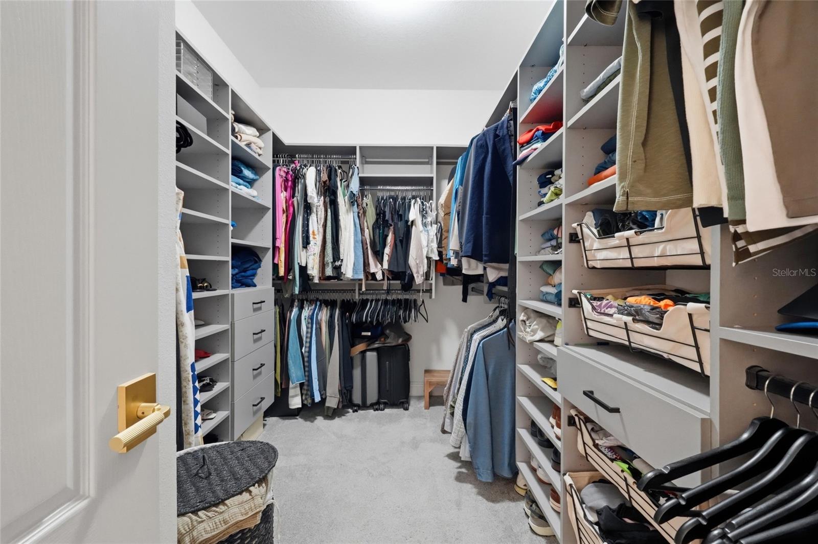 Walk-in closet with built-in shelving, hanging clothes, drawers, and shoe storage.