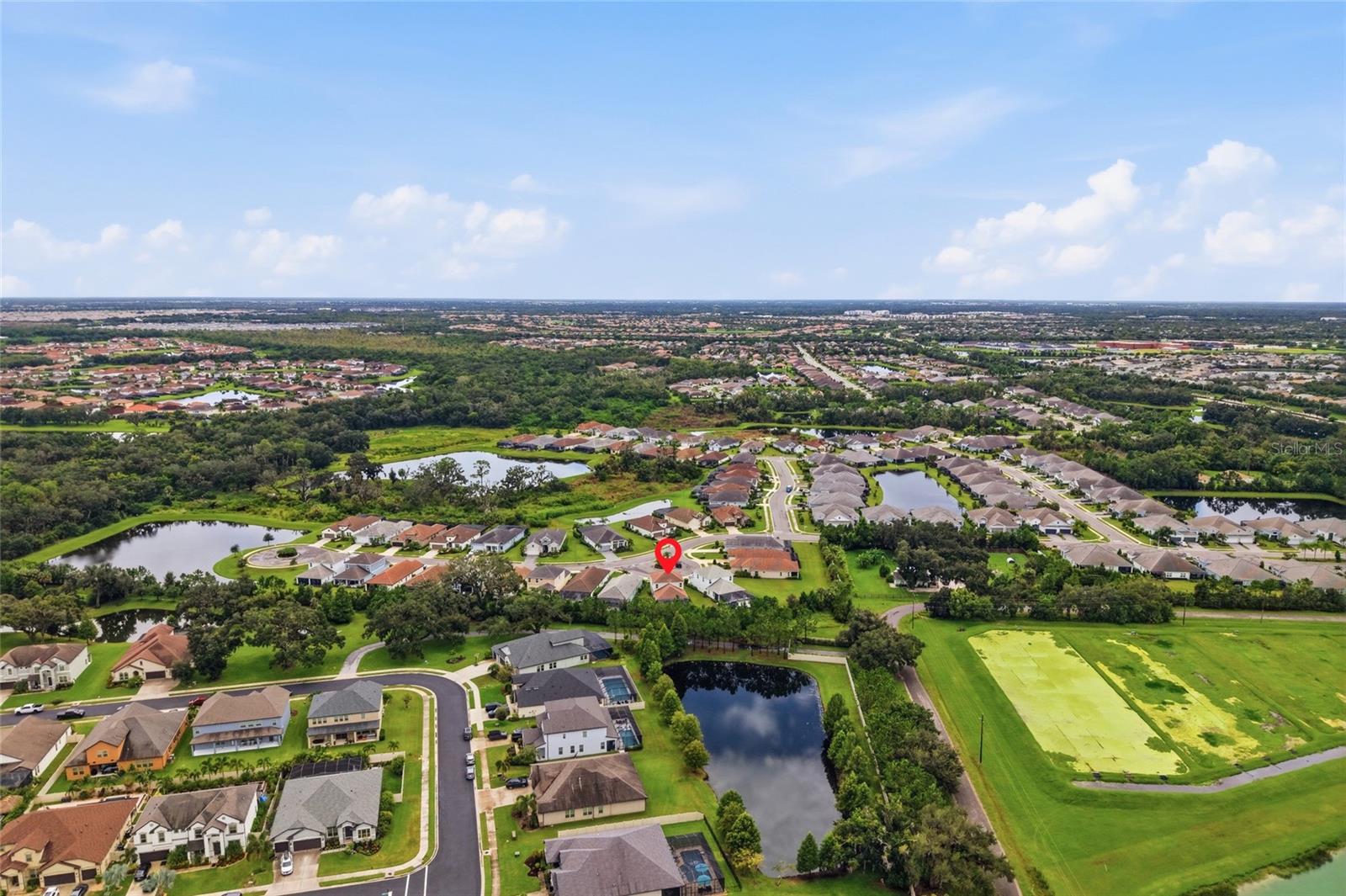 Aerial view of a home marked with a red pin in a community with ponds and green space.