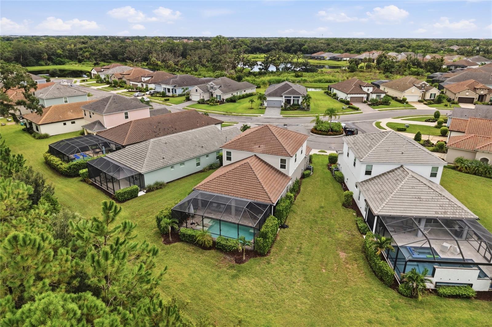 Aerial view of a residential neighborhood with screened pool enclosures, lawns, and ponds.