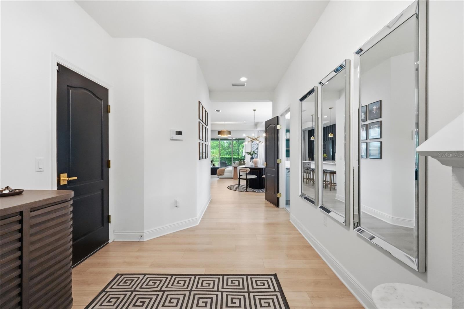 Modern entry hallway with mirrored wall, geometric runner, and view into the dining area.
