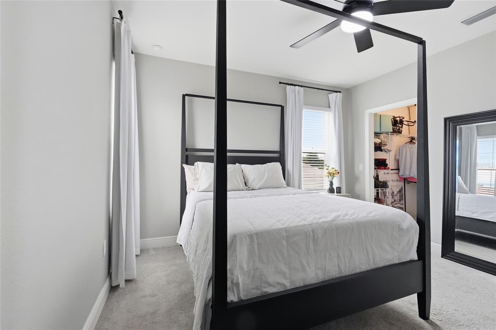 Bedroom with a black four-poster bed, white bedding, and an open closet.