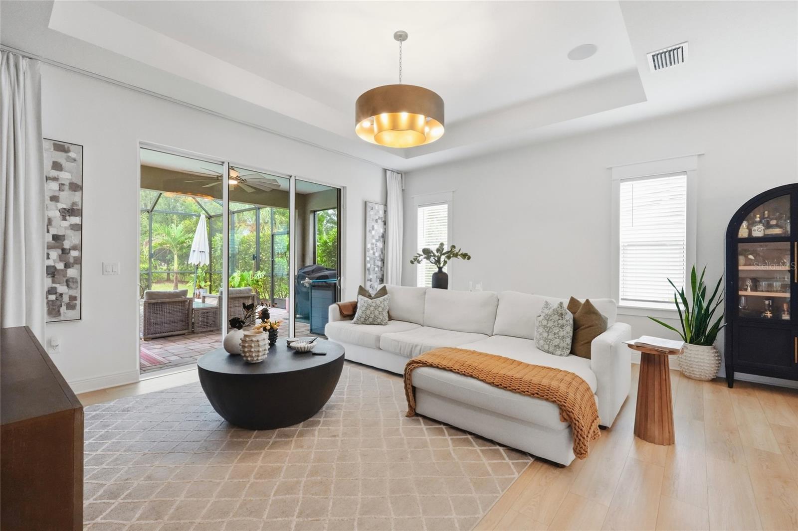 Living room with a white sectional and coffee table beside sliding doors to a screened patio.