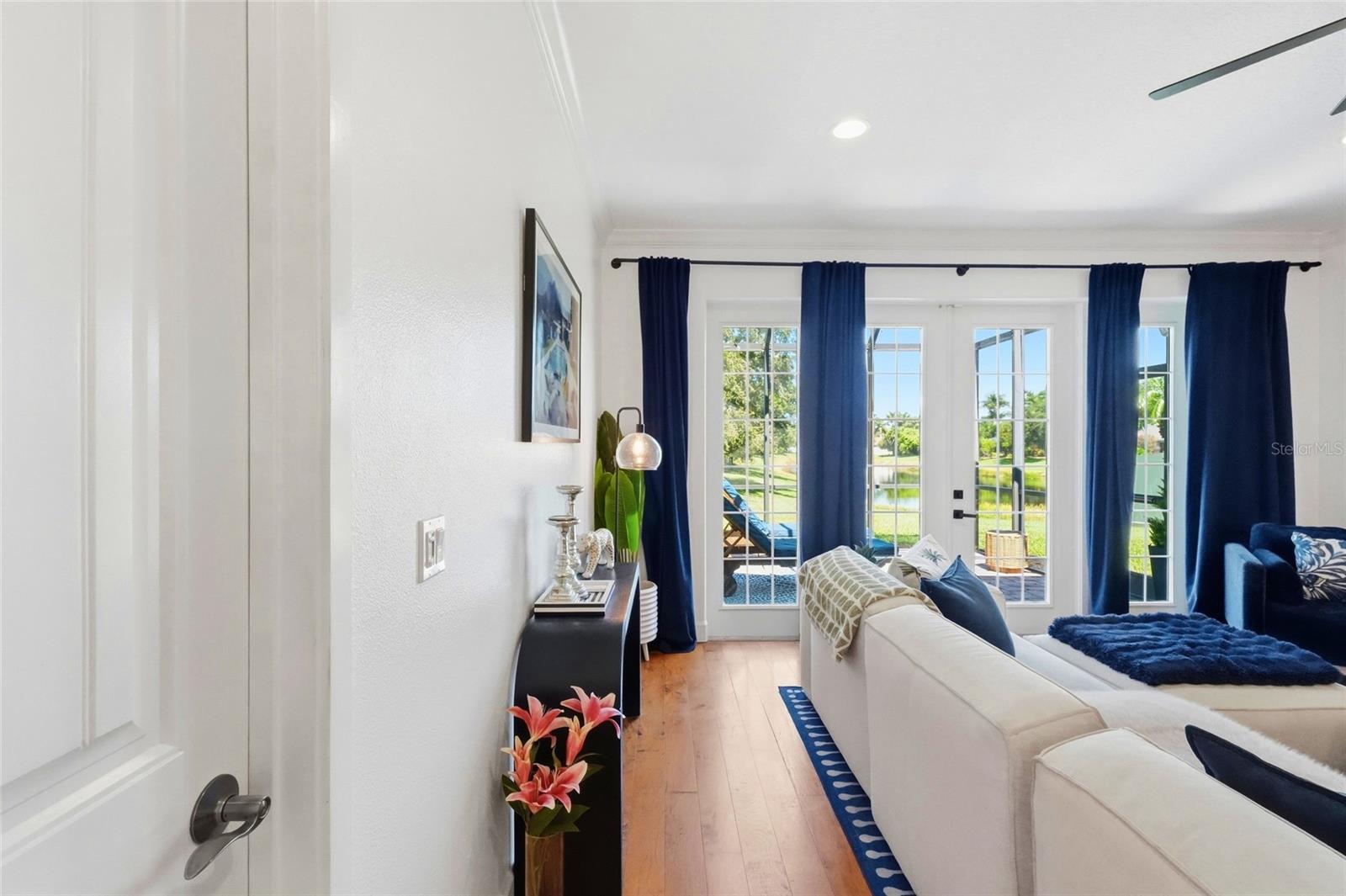 Furnished living room with navy curtains and glass doors overlooking a pond.