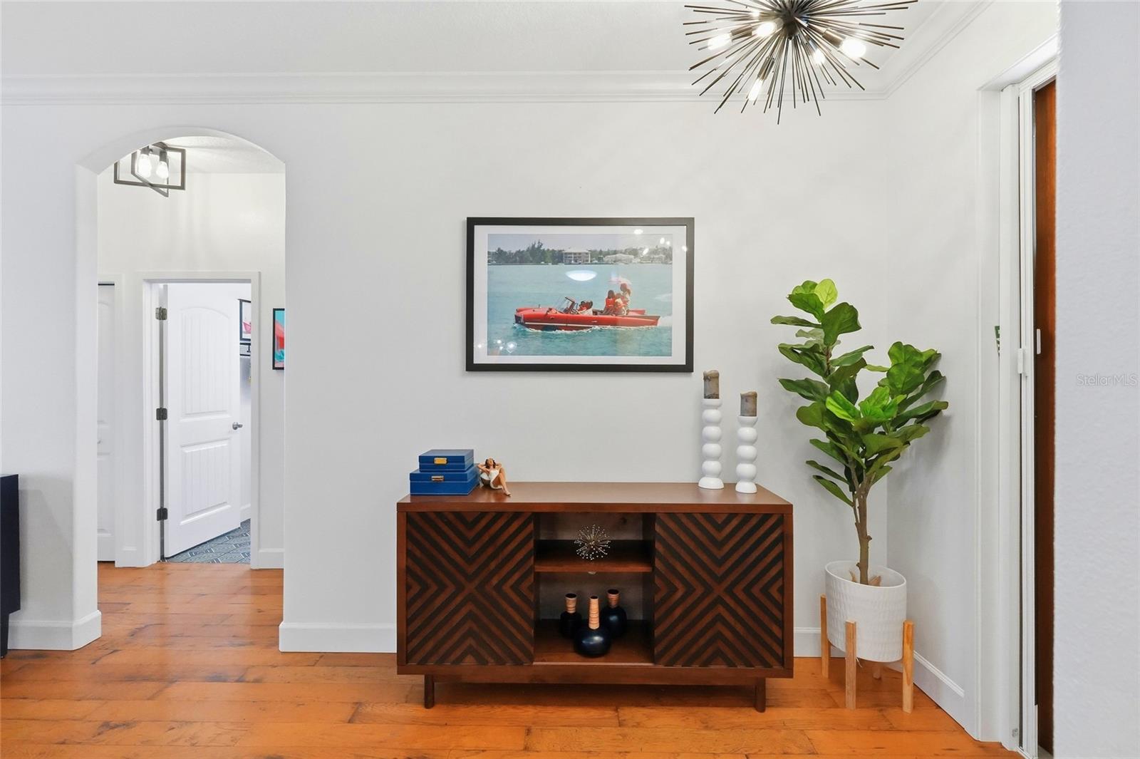Foyer with a patterned wooden console, arched doorway, and potted tree.