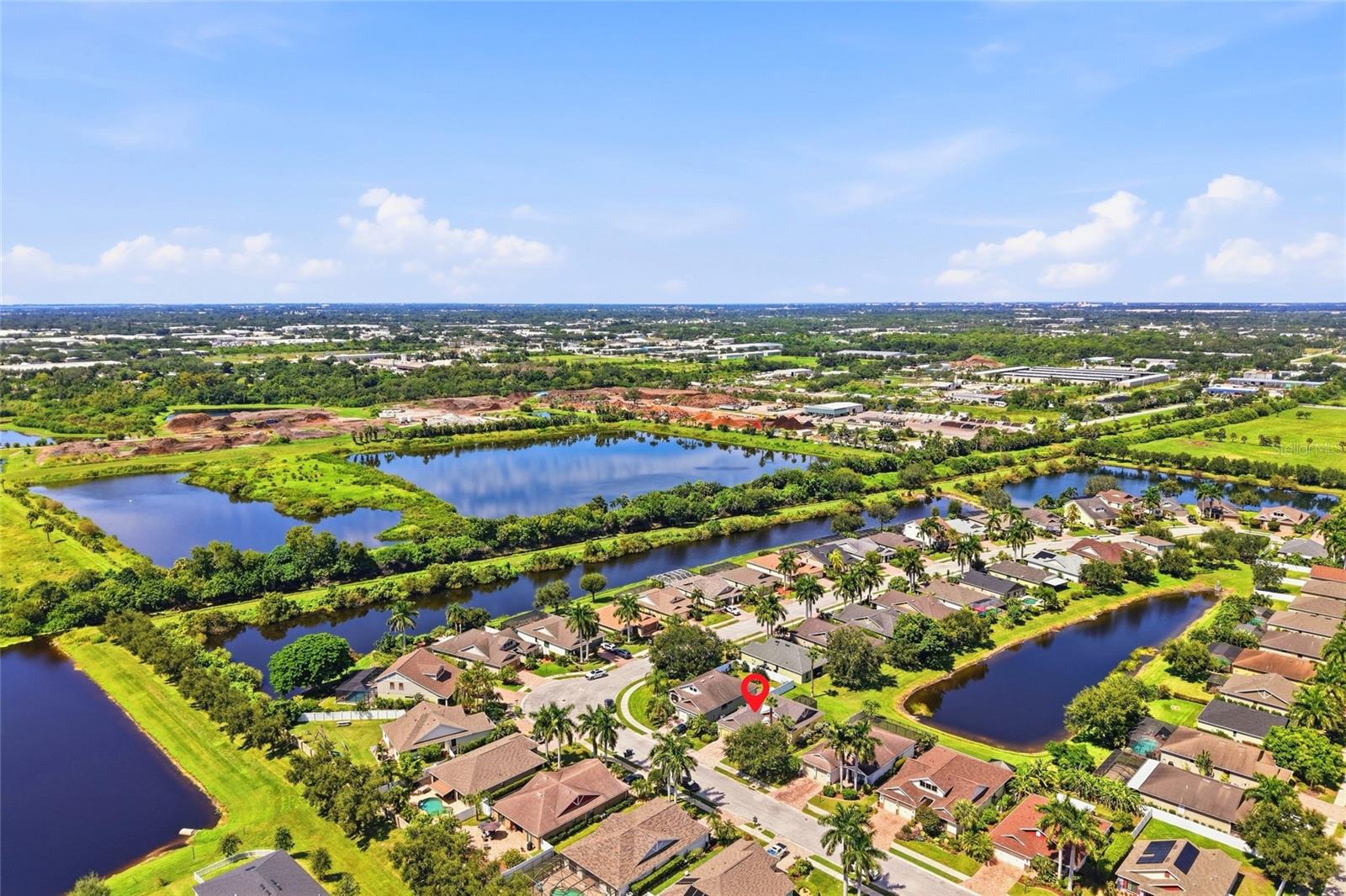 Aerial neighborhood view with the marked home beside a pond and canal.