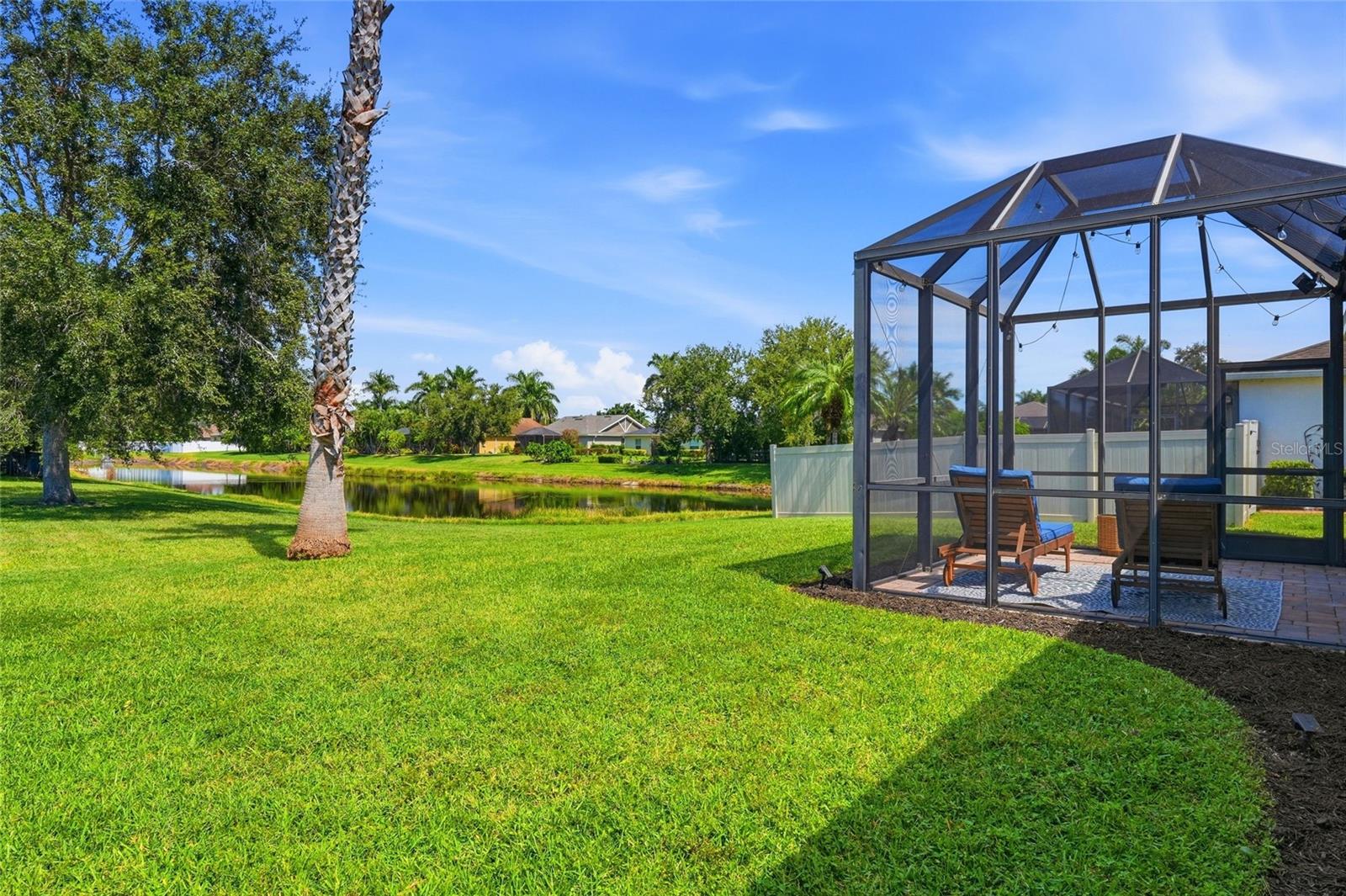 Backyard with a screened patio enclosure, lawn, and pond view.
