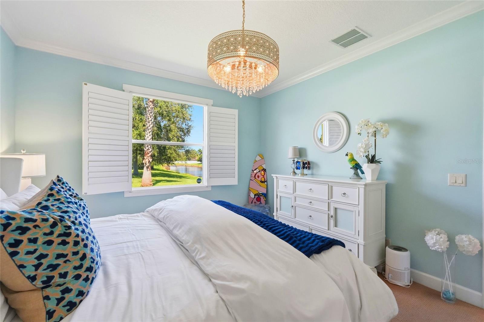 Bedroom with aqua walls, a crystal chandelier, and a window overlooking water.