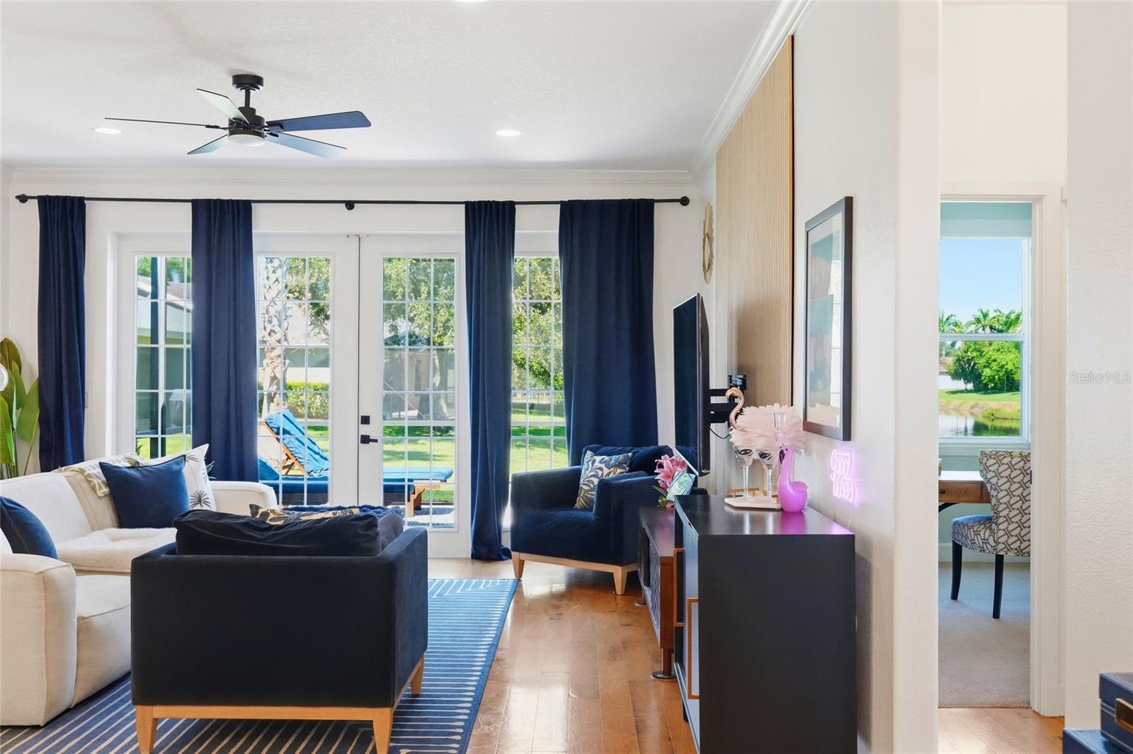 Living room with navy and white seating, blue curtains, and French doors overlooking the yard.