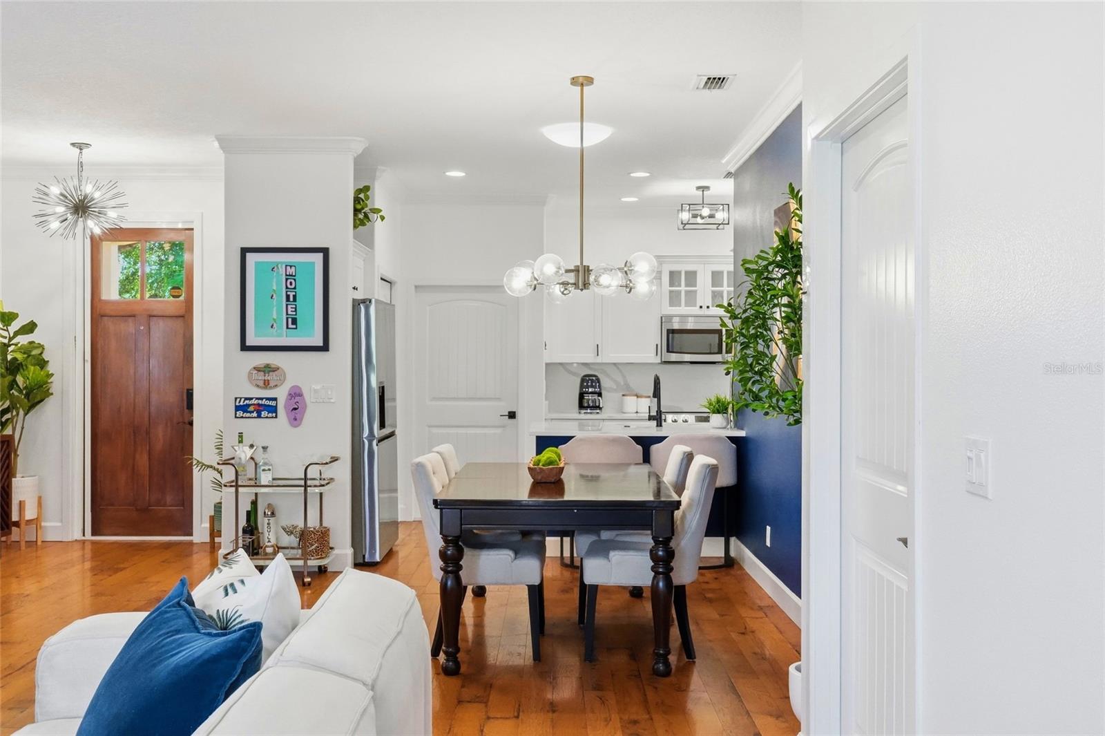 Open dining area with dark table, white kitchen cabinetry, and warm wood floors.
