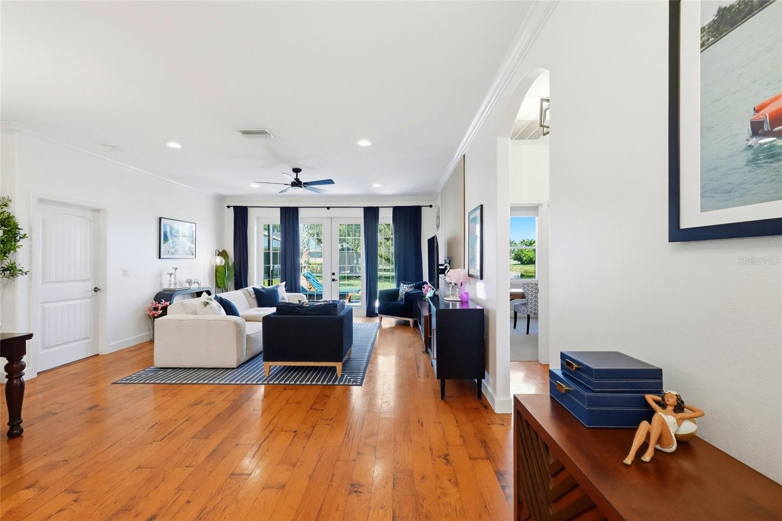 Furnished living room with hardwood floors, navy seating, and glass doors to the backyard.